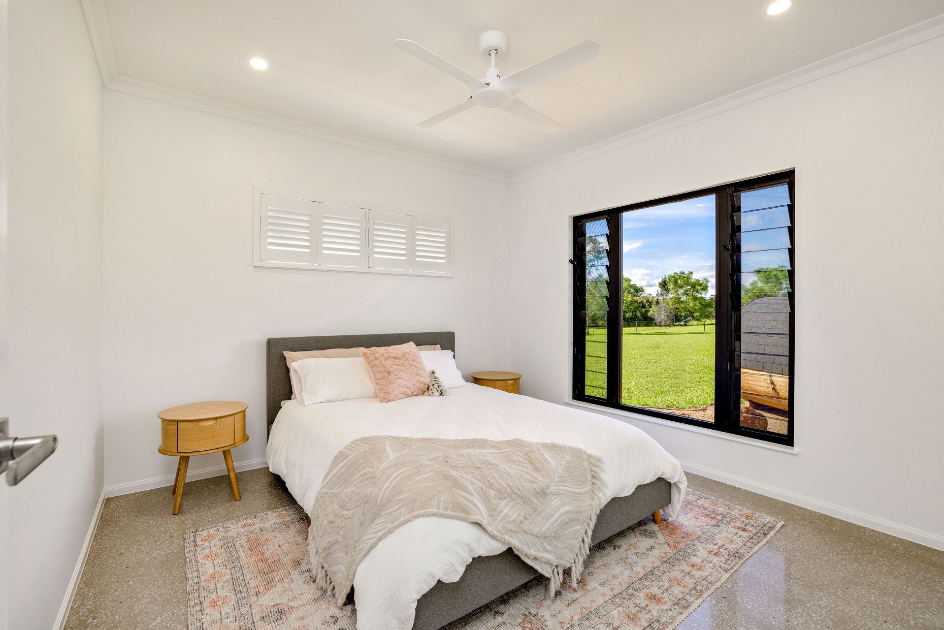 A Bright, Modern Bedroom Featuring a Queen Bed With a Grey Frame — Ashlee Jones Homes in Gordonvale, QLD