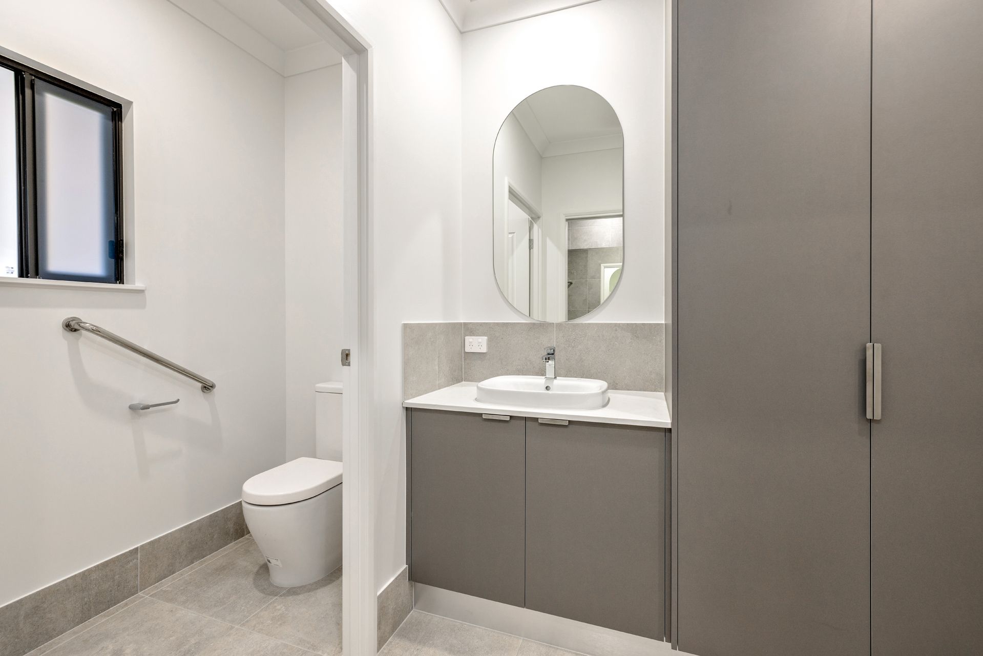 A Bathroom Featuring an Accessible Toilet With a Grab Rail — Ashlee Jones Homes in Gordonvale, QLD