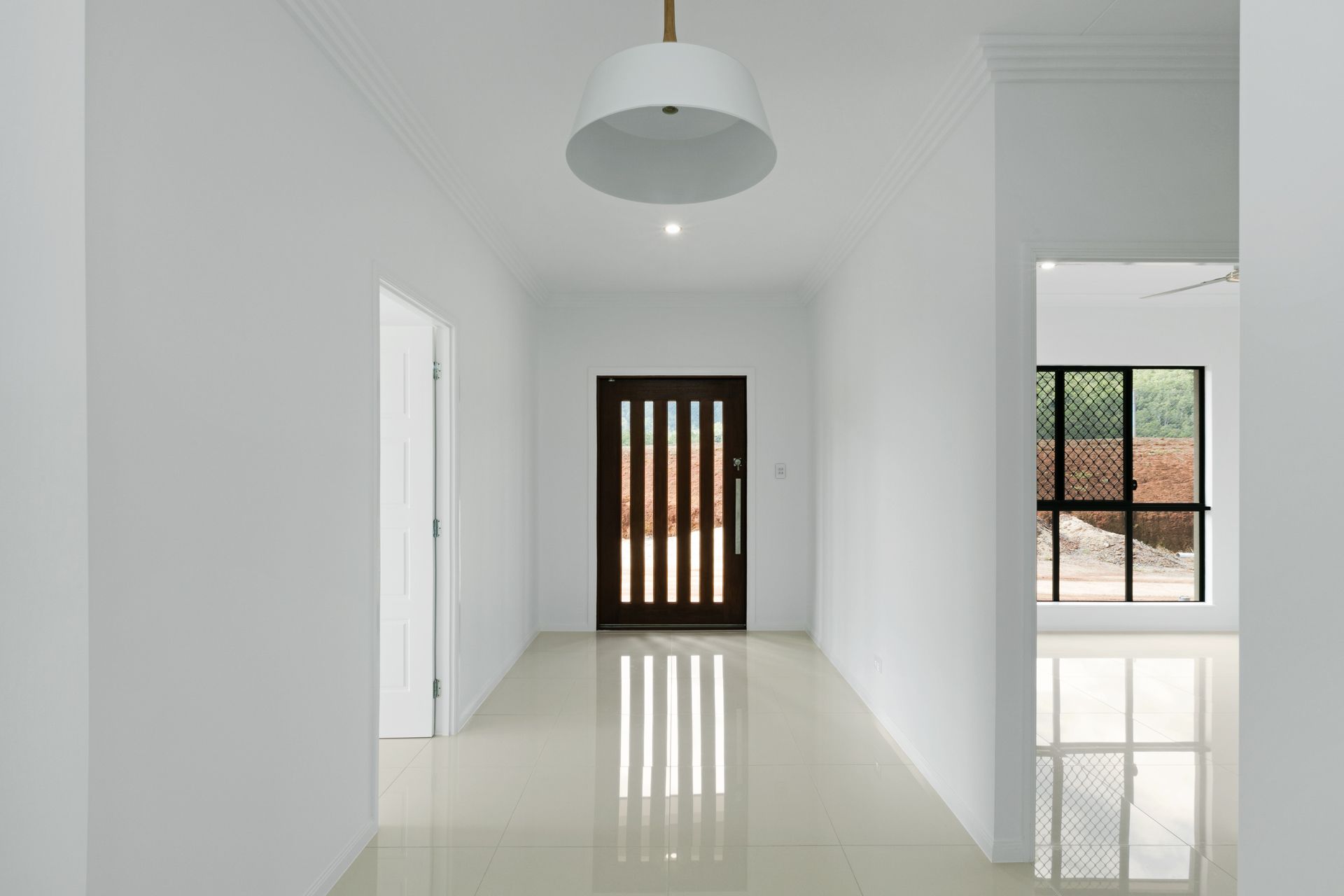 A Bright, Minimalist Hallway With Glossy White Floors — Ashlee Jones Homes in Gordonvale, QLD