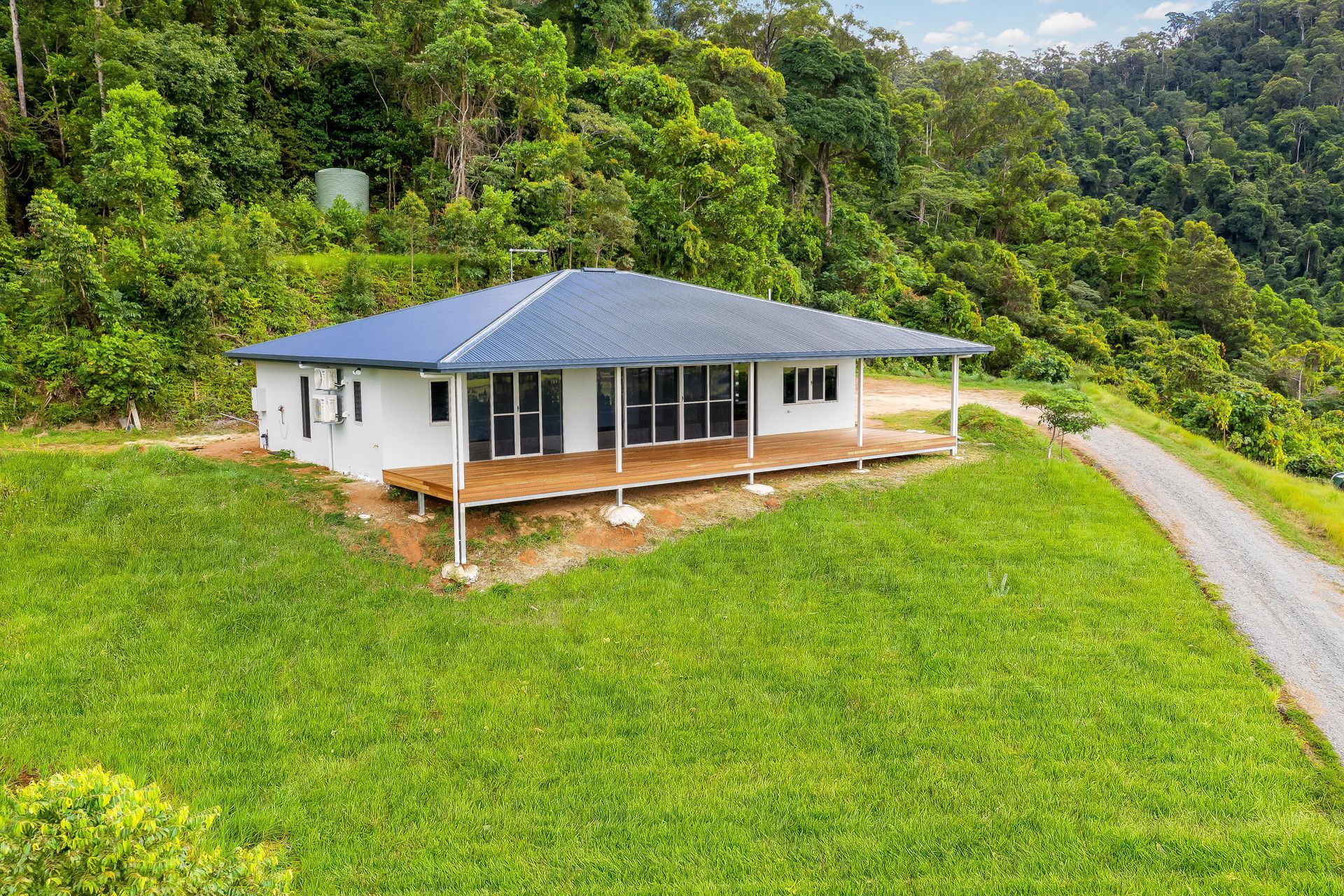 A Modern, White Single-story House With a Blue Roof and Wooden Deck — Ashlee Jones Homes in Gordonvale, QLD