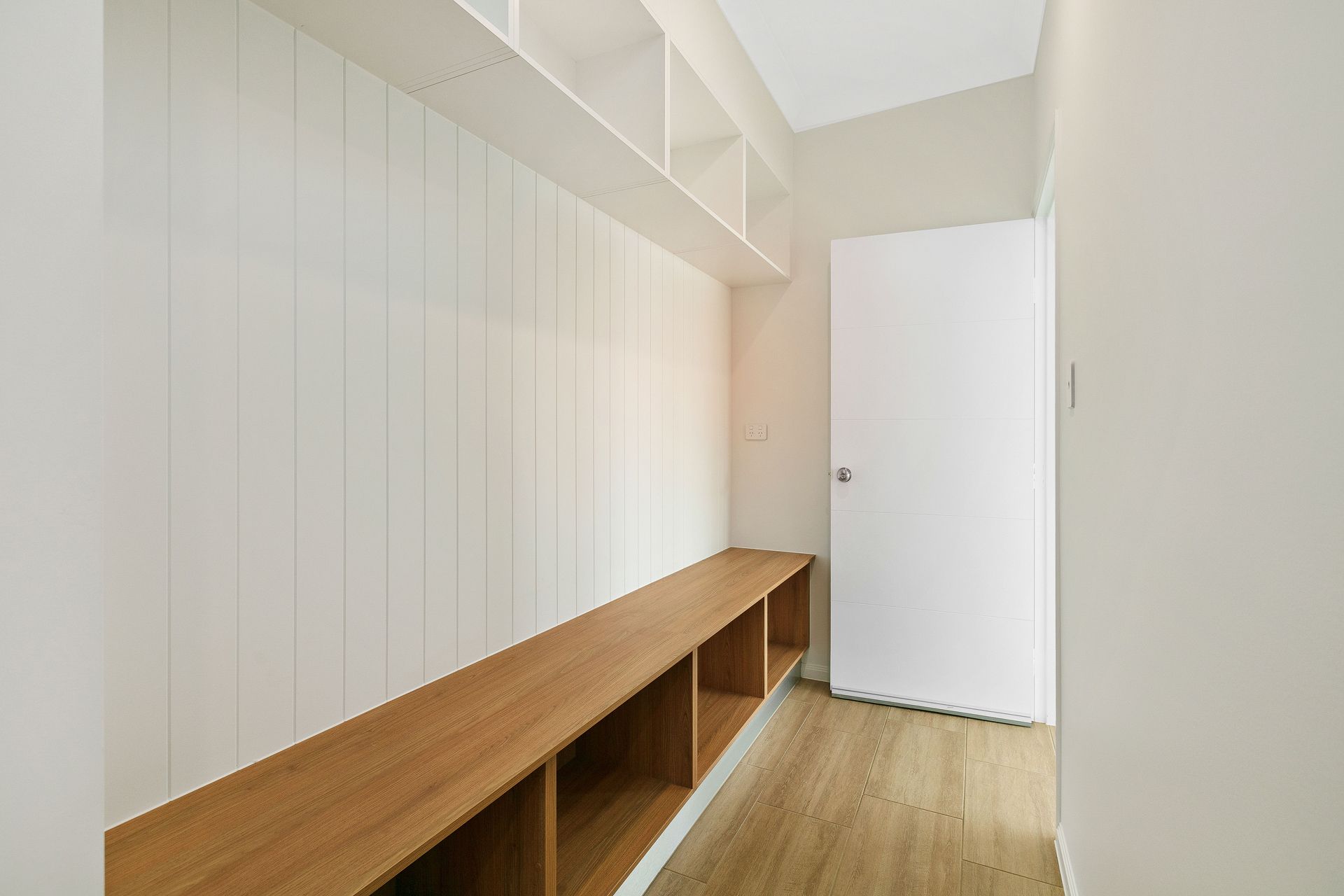 A Minimalist Mudroom Featuring a Light Wood Bench With Storage Cubbies — Ashlee Jones Homes in Gordonvale, QLD