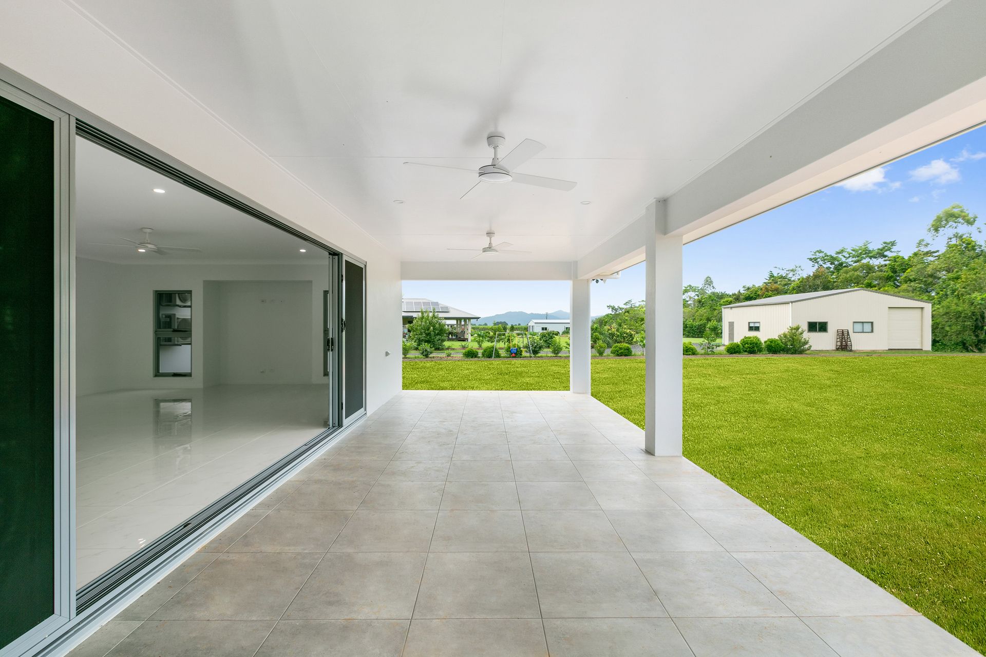 A Spacious, Modern Tiled Patio With Ceiling Fans — Ashlee Jones Homes in Gordonvale, QLD