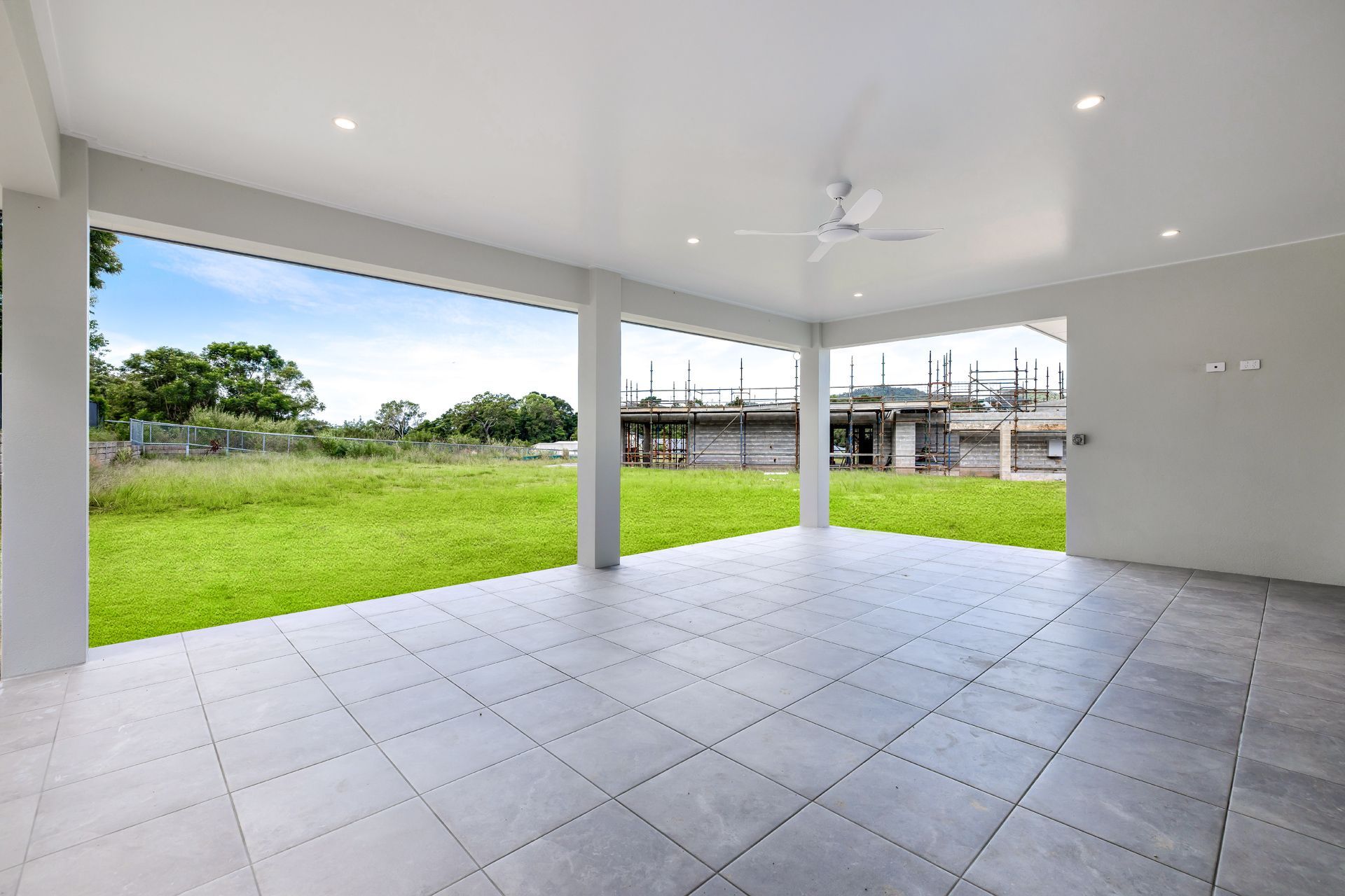A Covered Outdoor Patio With Light Gray Tiled Flooring — Ashlee Jones Homes in Gordonvale, QLD