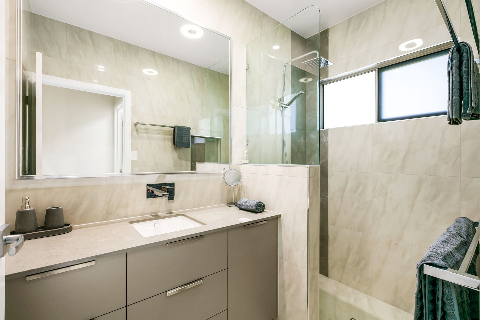 A Modern Bathroom Featuring a Gray Vanity With a White Sink — Ashlee Jones Homes in Gordonvale, QLD