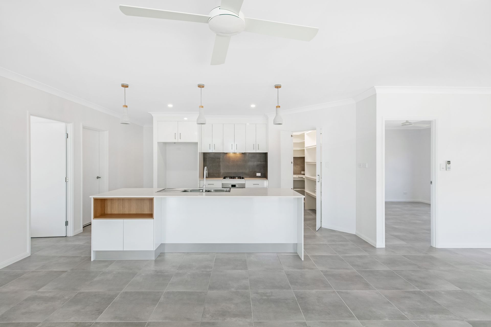 Modern, Minimalist Kitchen Featuring a White Island With Wood Accents — Ashlee Jones Homes in Gordonvale, QLD