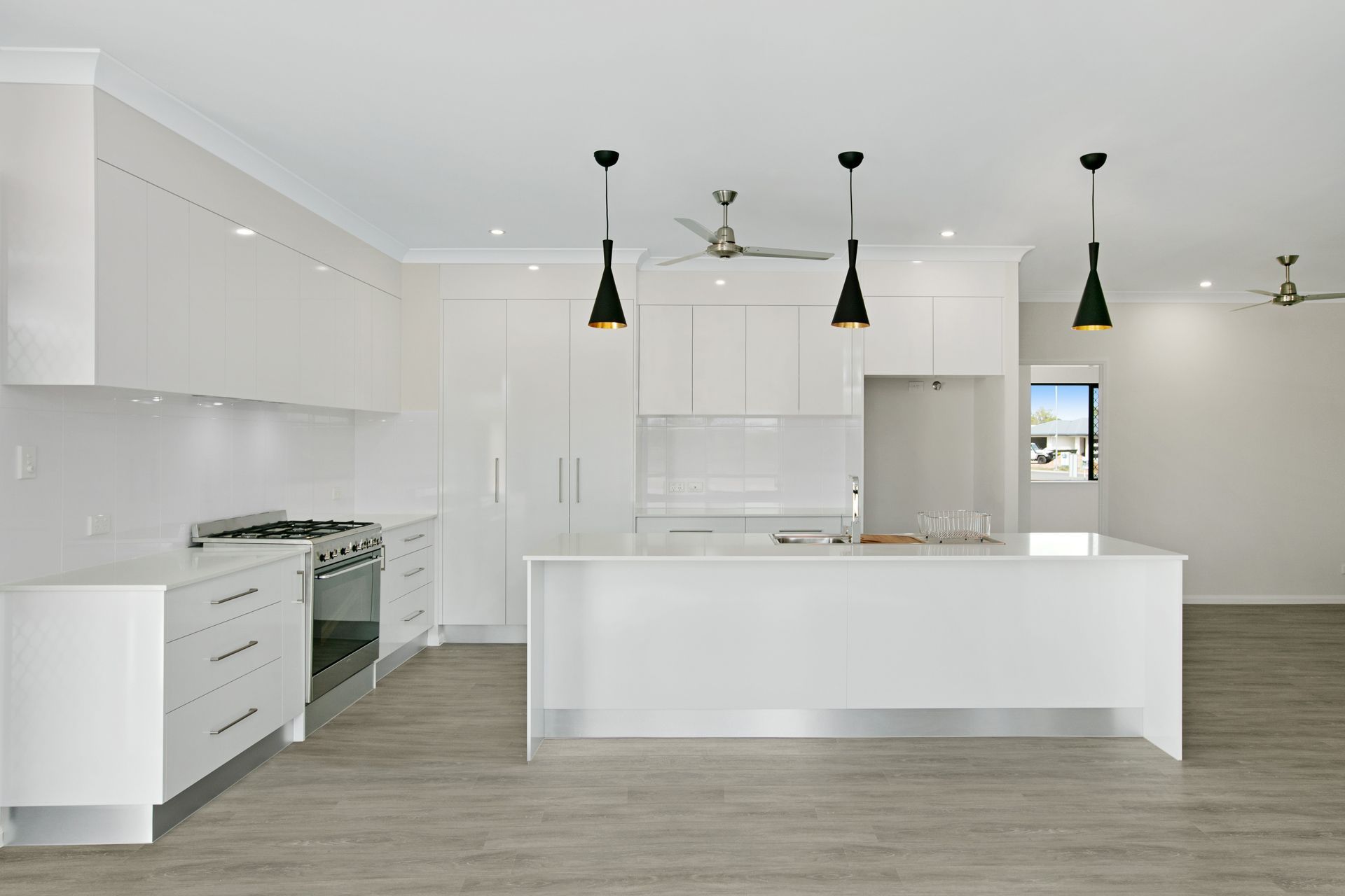 A Modern Kitchen With White Cabinetry, a Central Island — Ashlee Jones Homes in Gordonvale, QLD