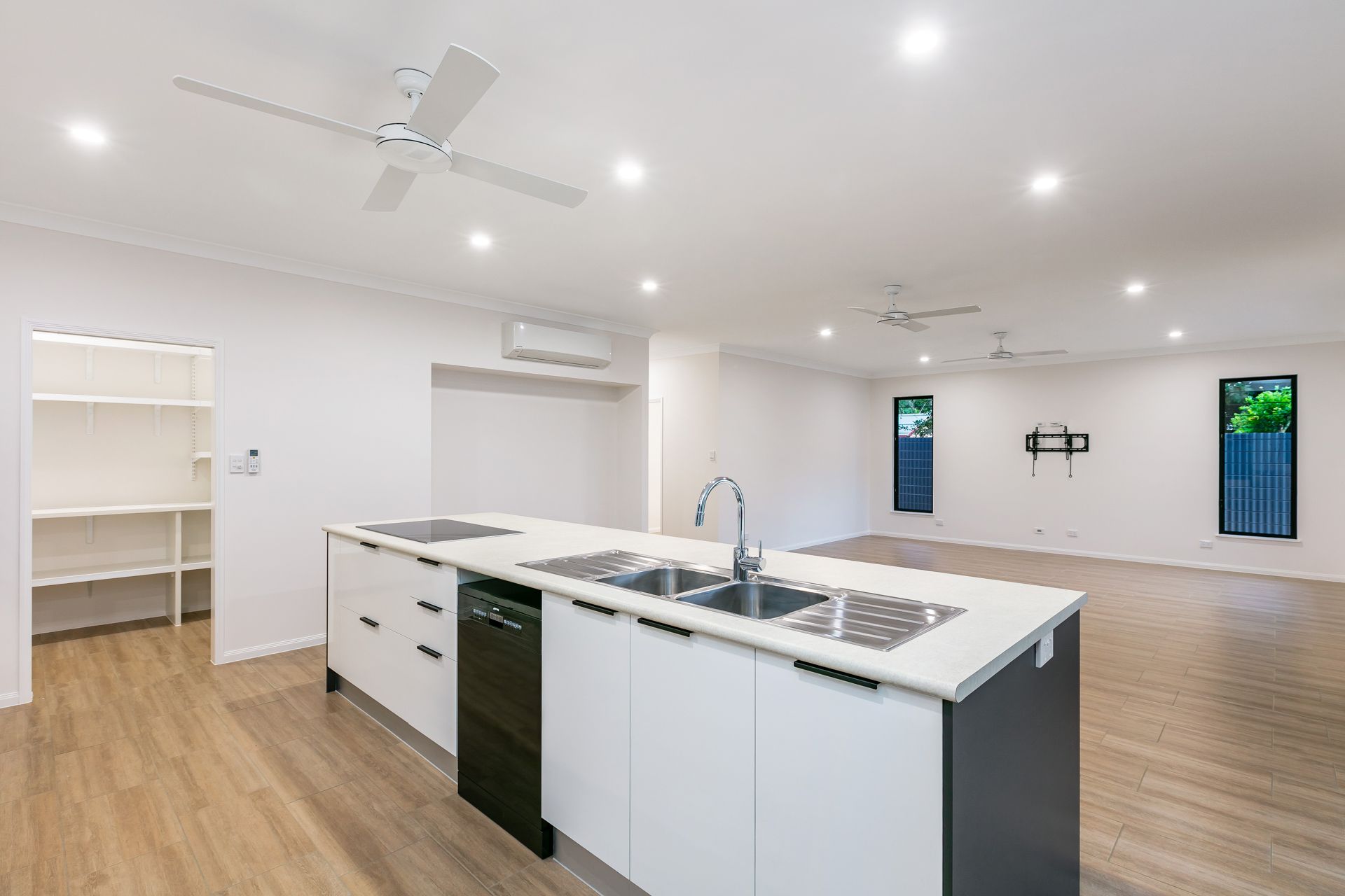 A Bright, Open-plan Kitchen and Living Area Featuring White Cabinets — Ashlee Jones Homes in Gordonvale, QLD
