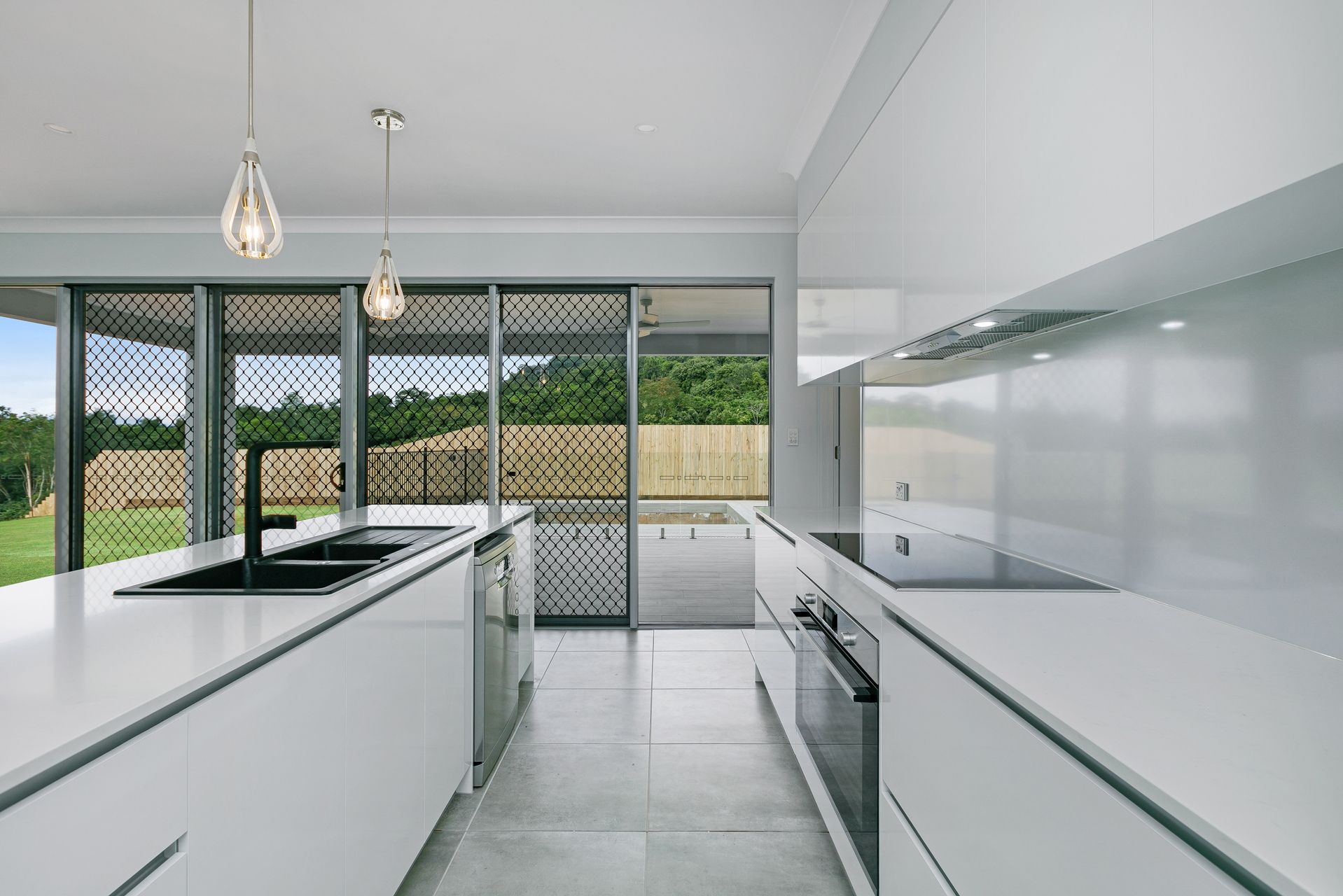 A Modern White Kitchen Featuring a Large Island — Ashlee Jones Homes in Gordonvale, QLD