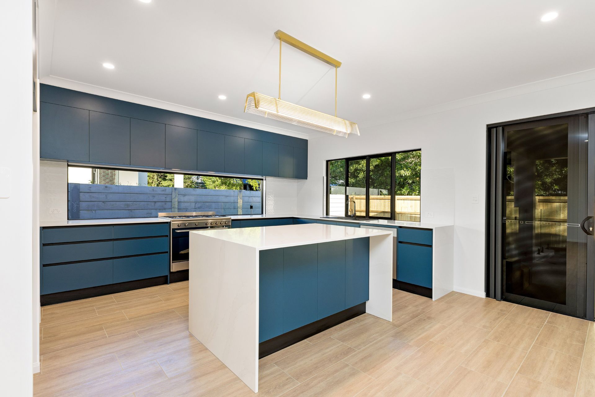 Modern Kitchen With Blue Cabinetry, a White Waterfall Island — Ashlee Jones Homes in Gordonvale, QLD
