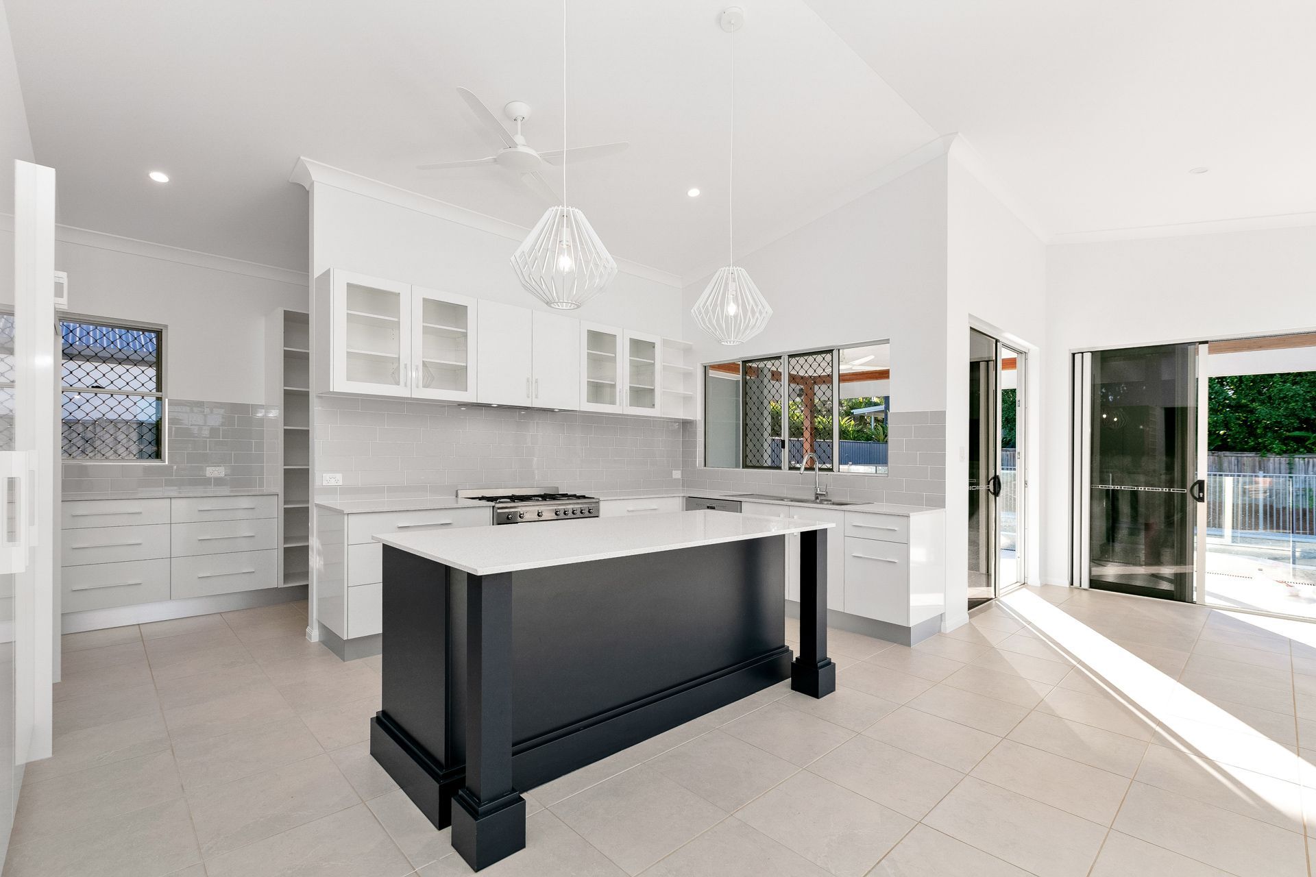 Modern Kitchen With a Dark Central Island, White Cabinetry — Ashlee Jones Homes in Gordonvale, QLD