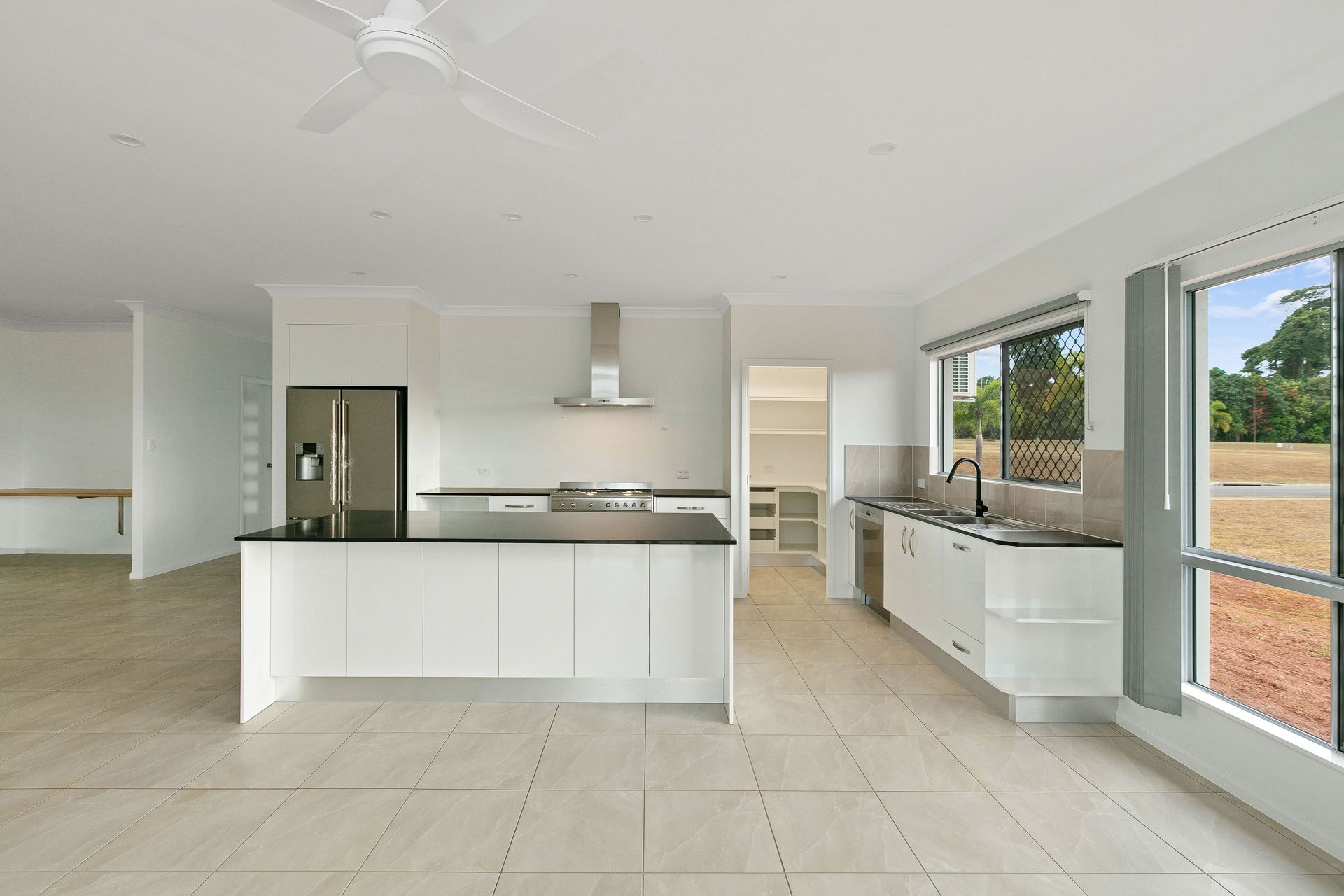 A Bright, Open-plan Kitchen With White Cabinets, Dark Countertops — Ashlee Jones Homes in Gordonvale, QLD