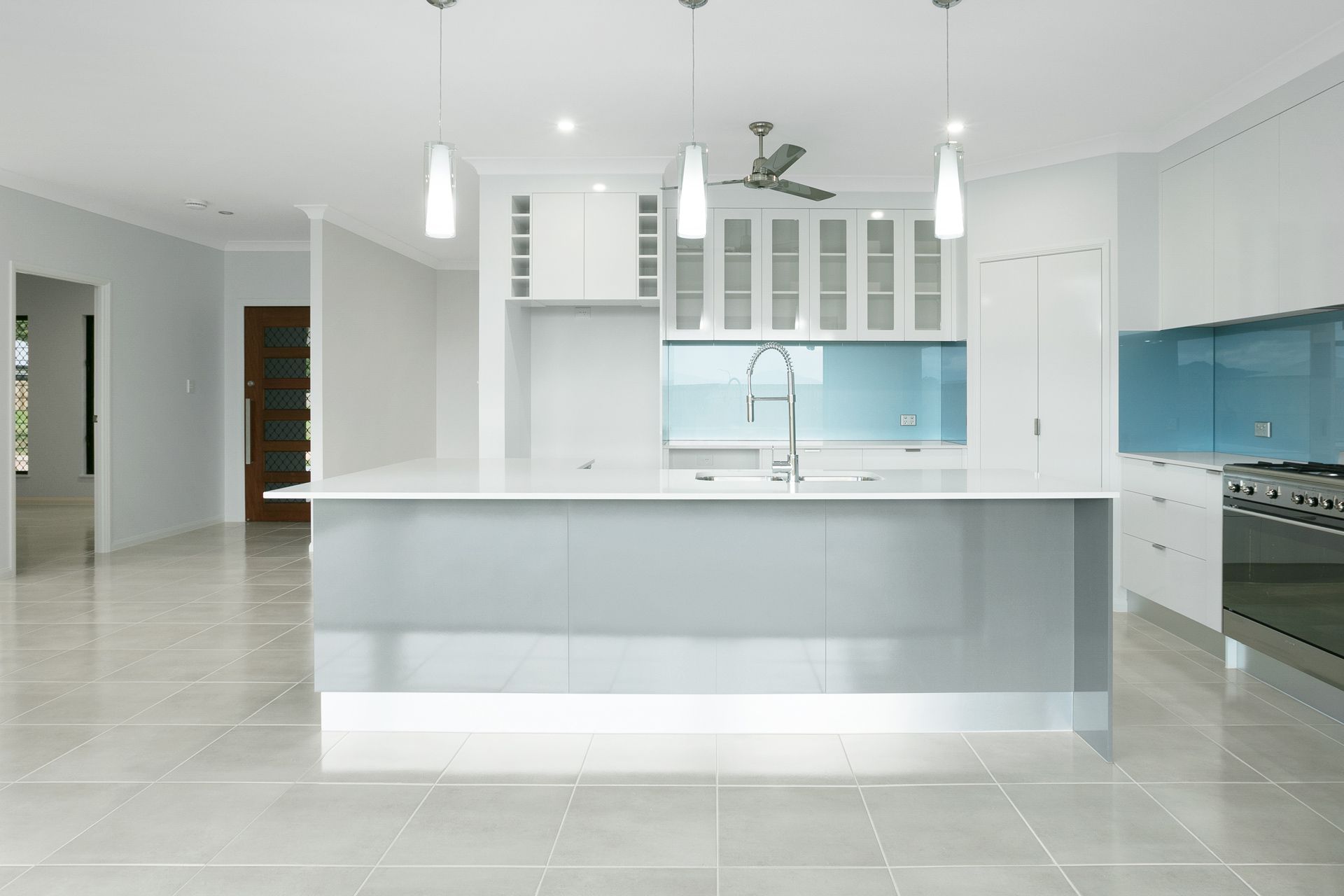 Modern Kitchen With a Large Gray Island, White Cabinets — Ashlee Jones Homes in Gordonvale, QLD
