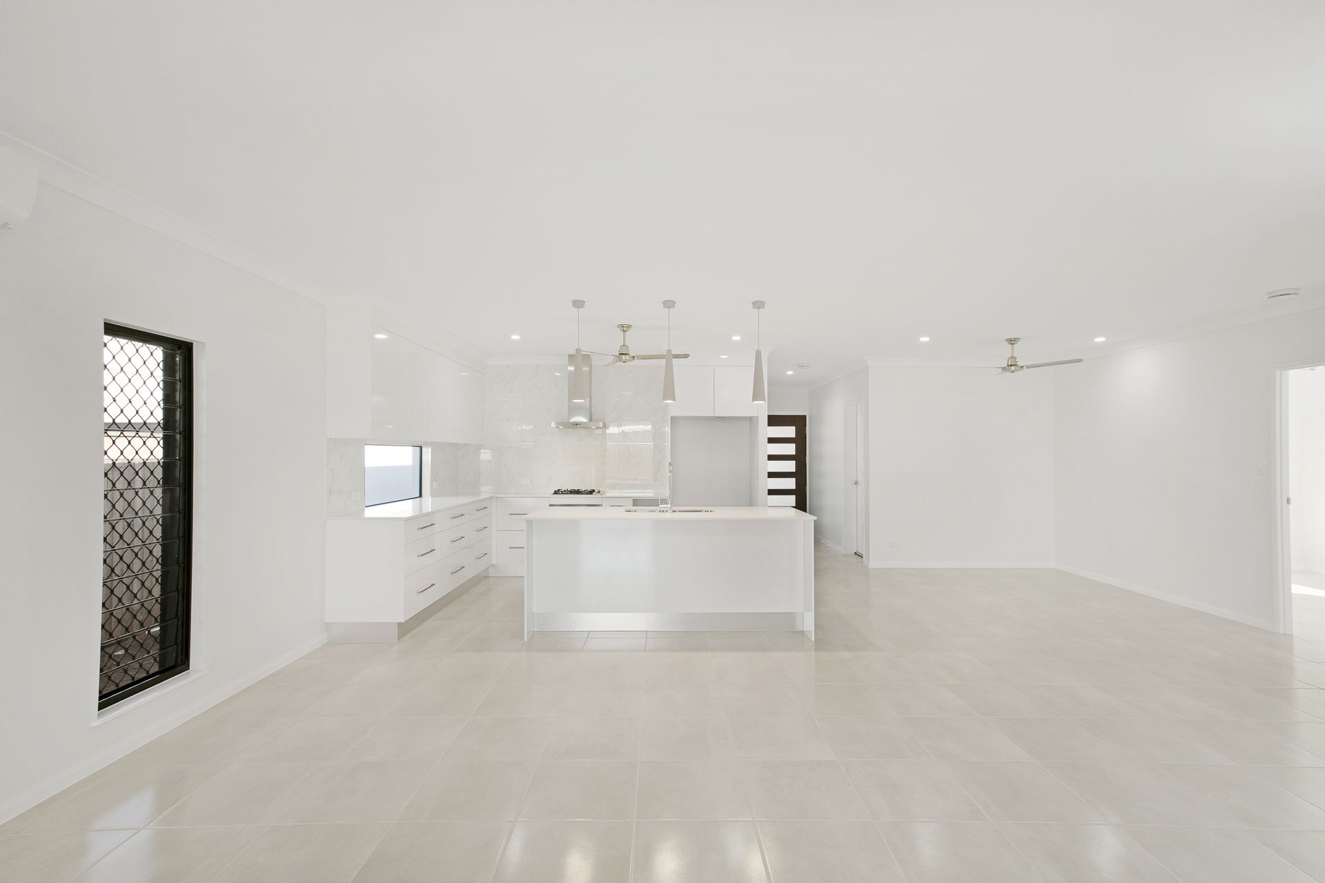 An Open-plan Kitchen With White Cabinetry, a Center Island — Ashlee Jones Homes in Gordonvale, QLD