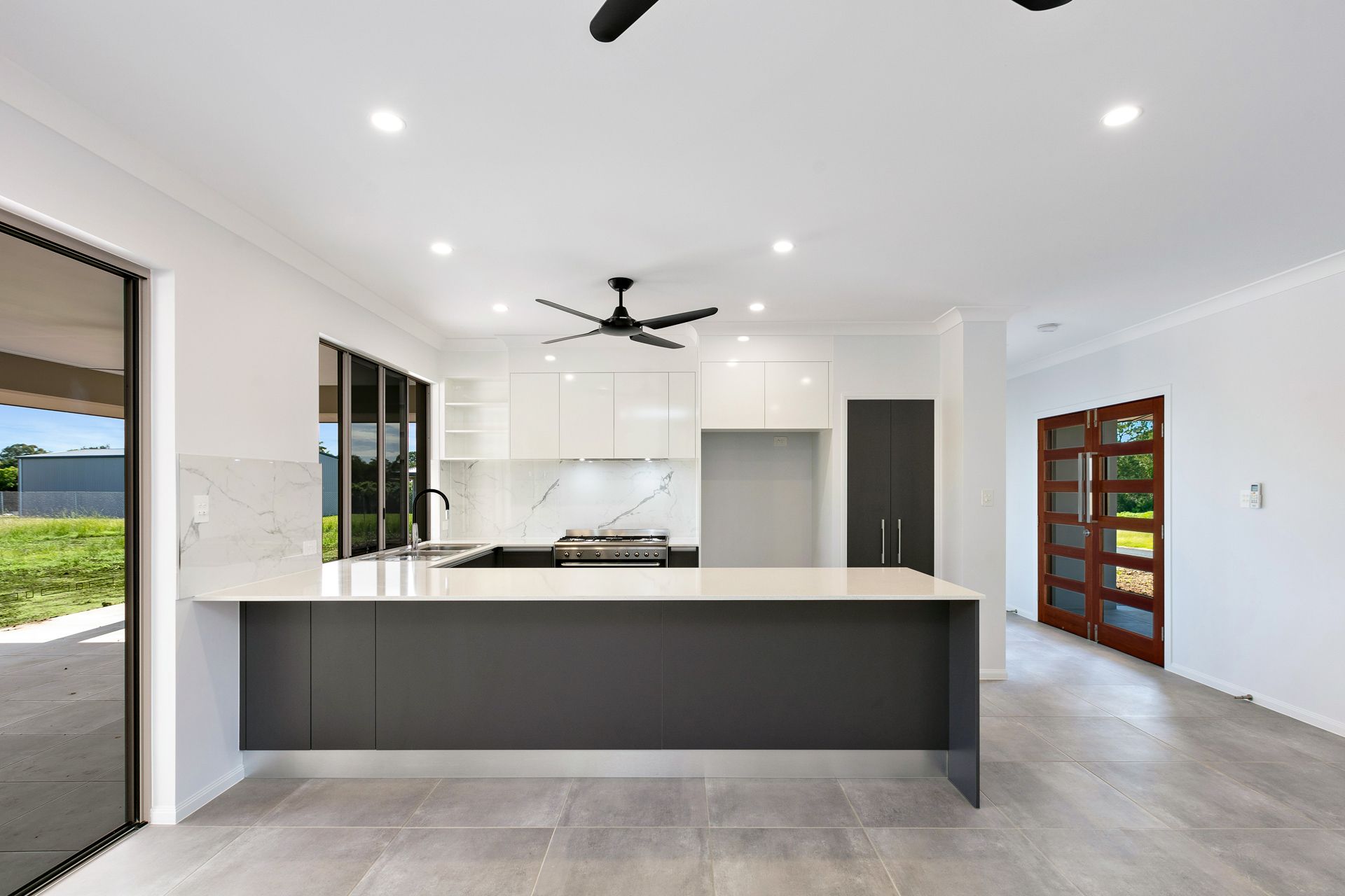 Modern Kitchen With a Long Dark Grey Breakfast Bar — Ashlee Jones Homes in Gordonvale, QLD