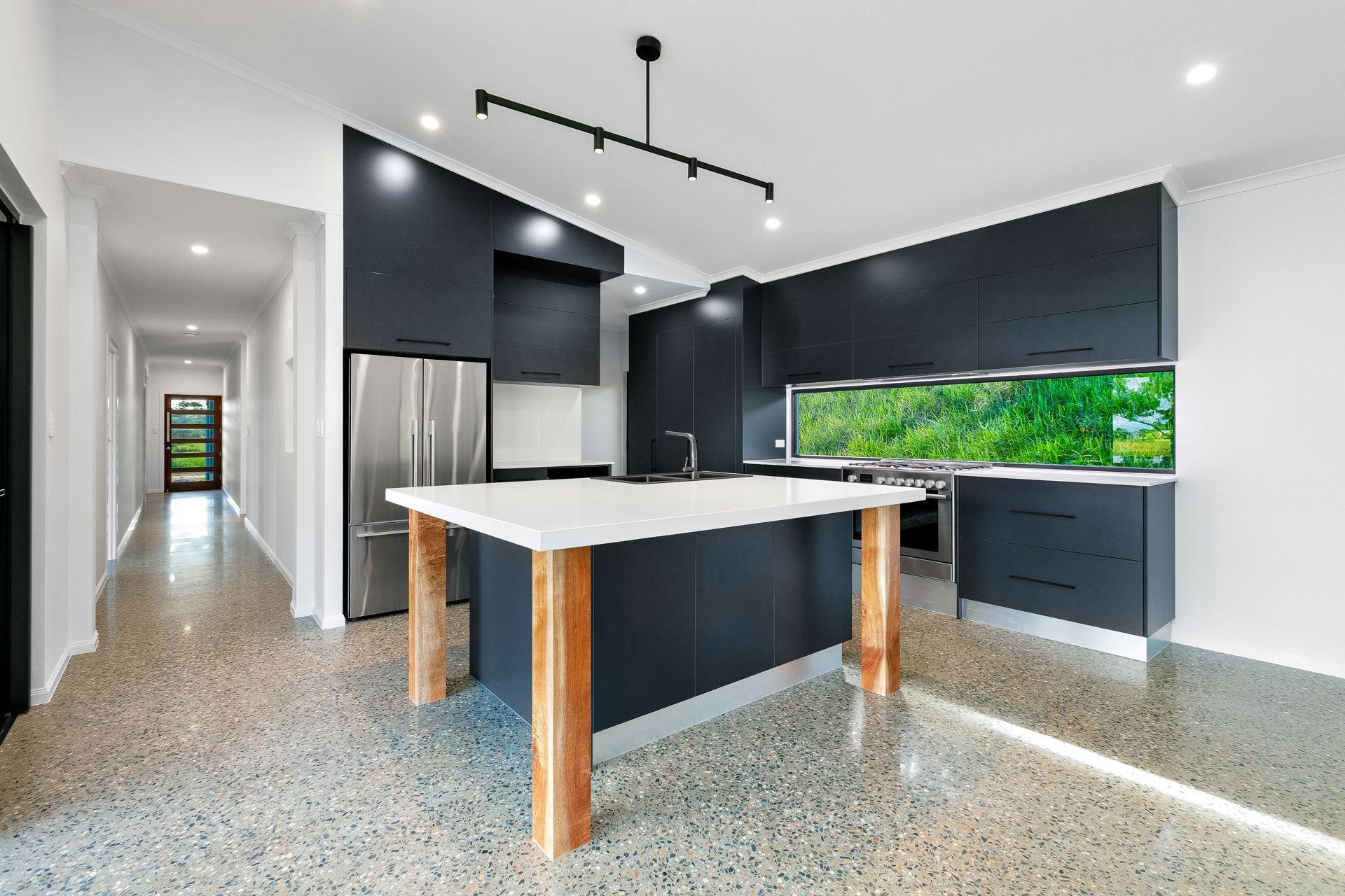 Modern Kitchen With Dark Cabinetry, White Island With Wooden Legs — Ashlee Jones Homes in Gordonvale, QLD
