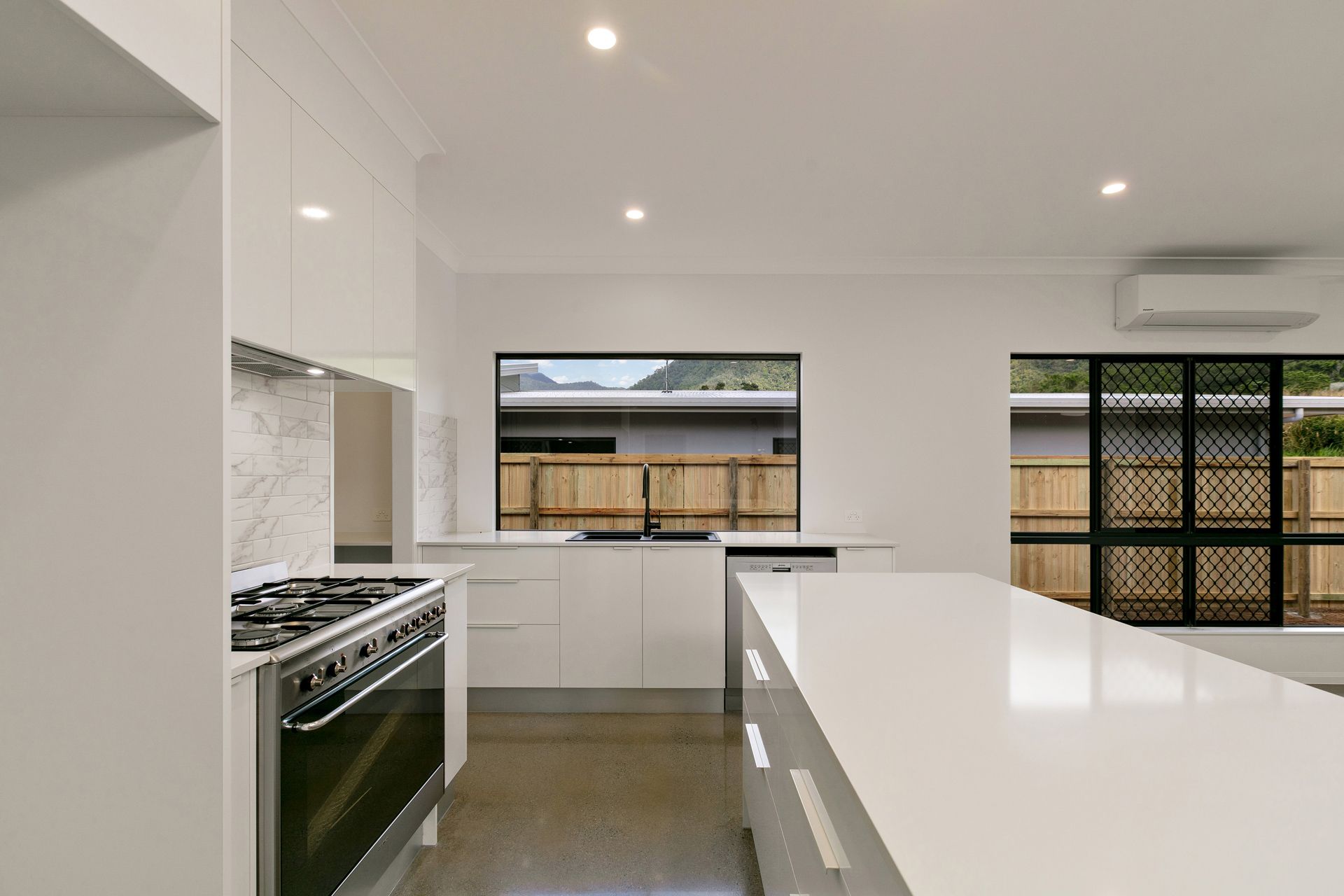 A Modern Kitchen With White Cabinetry, a Large Kitchen Island — Ashlee Jones Homes in Gordonvale, QLD
