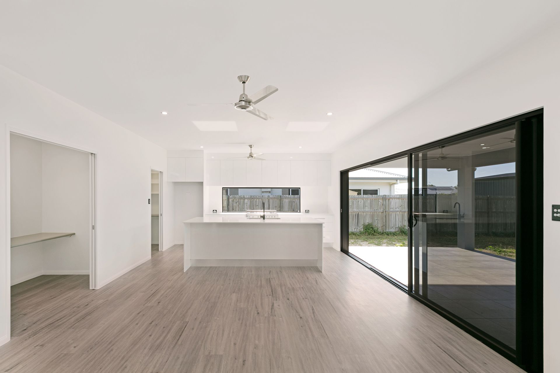 Minimalist, Open-plan Kitchen and Living Space With White Walls — Ashlee Jones Homes in Gordonvale, QLD