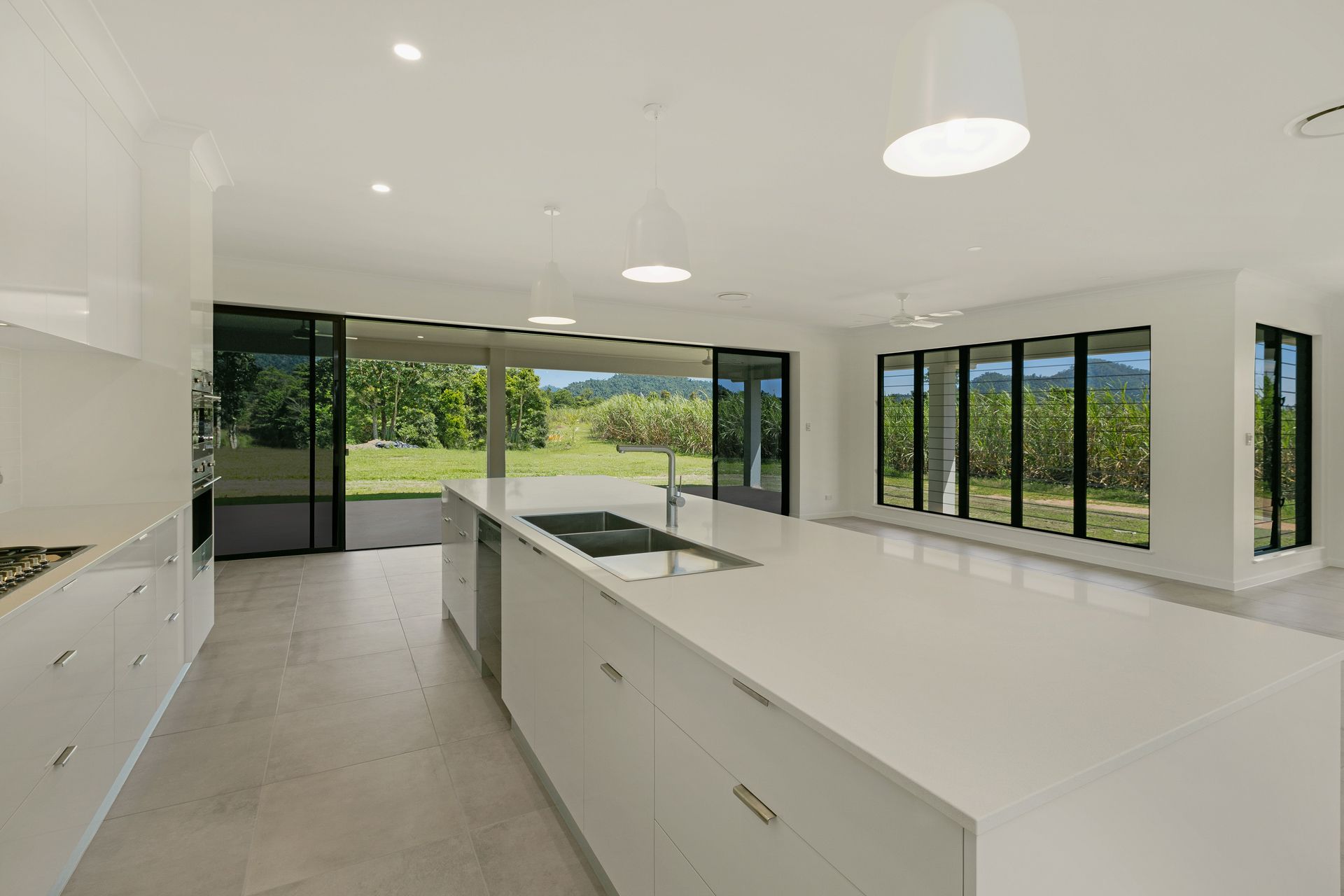 A Minimalist Modern Kitchen With White Cabinetry — Ashlee Jones Homes in Gordonvale, QLD