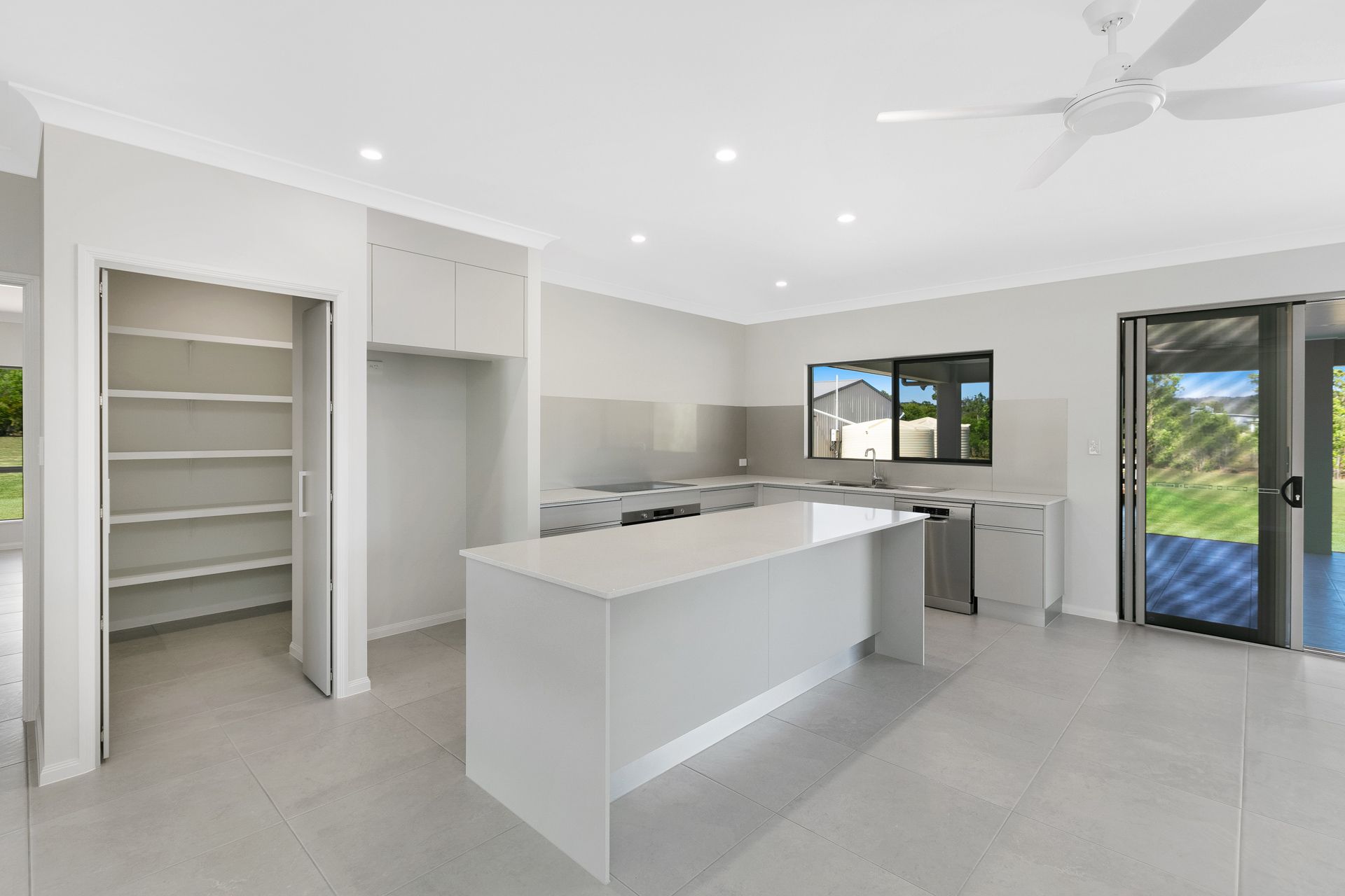 A Modern, Minimalist Kitchen Featuring a White Central Island — Ashlee Jones Homes in Gordonvale, QLD