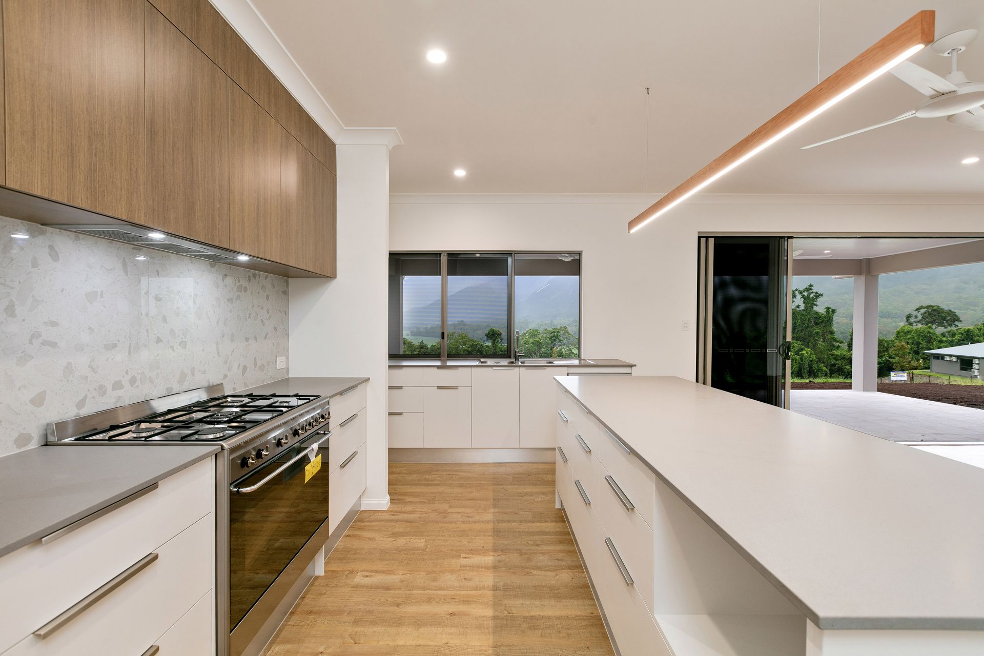 A Modern Kitchen Featuring White Cabinets, Wood-tone Upper Cabinets — Ashlee Jones Homes in Gordonvale, QLD