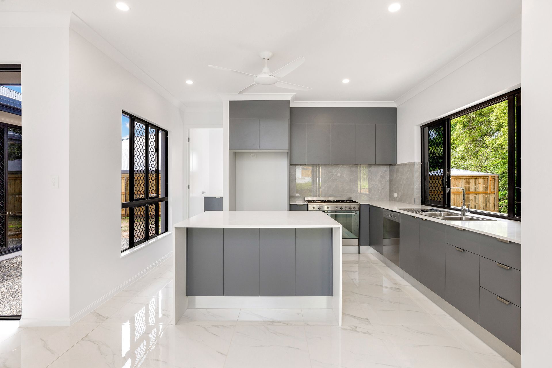 Modern Kitchen With a Gray Island, White Marble-style Flooring — Ashlee Jones Homes in Gordonvale, QLD