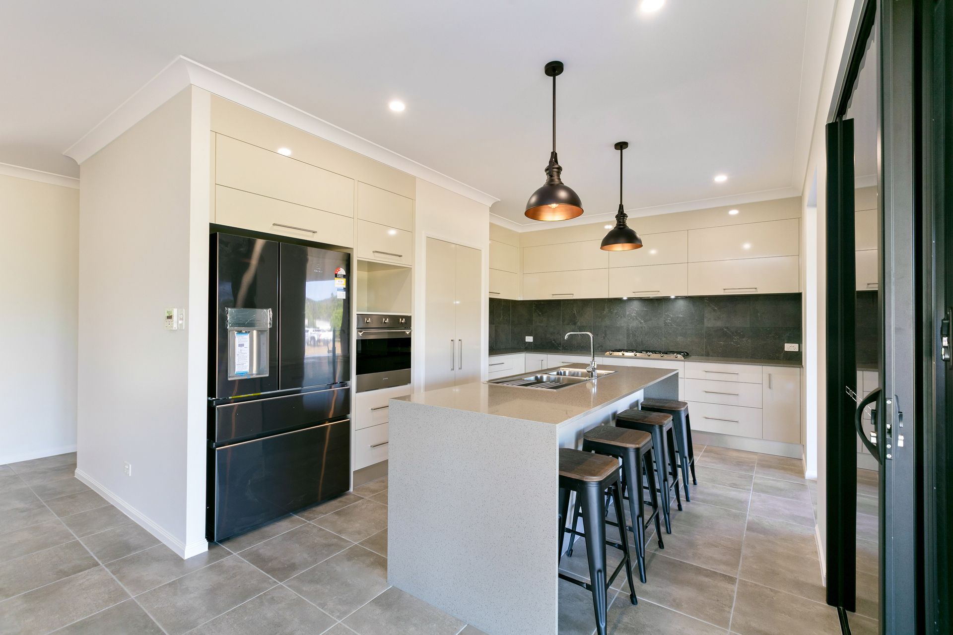 Modern Kitchen With Beige Cabinets, a Black Refrigerator — Ashlee Jones Homes in Gordonvale, QLD
