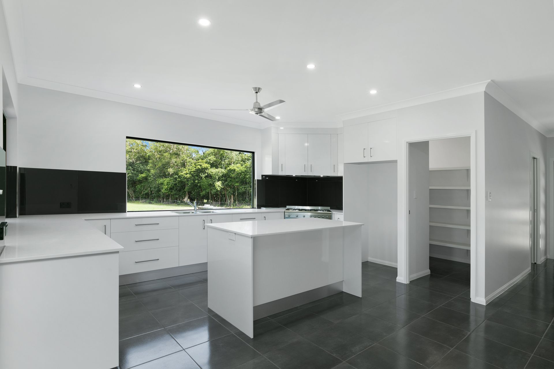 A Modern Kitchen With White Cabinets, a Central Island — Ashlee Jones Homes in Gordonvale, QLD