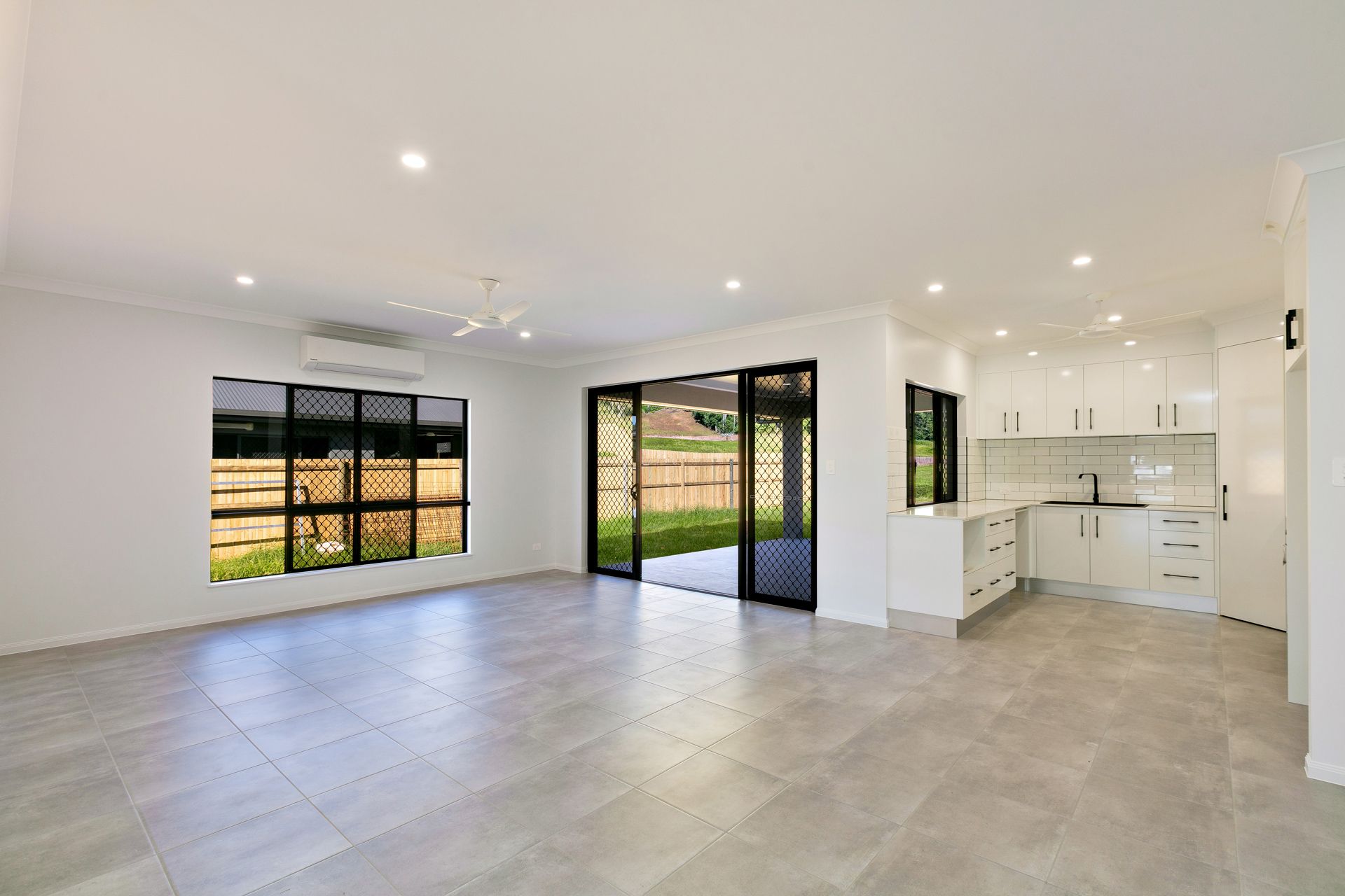 An Open-plan Living Room and Kitchen With White Walls — Ashlee Jones Homes in Gordonvale, QLD