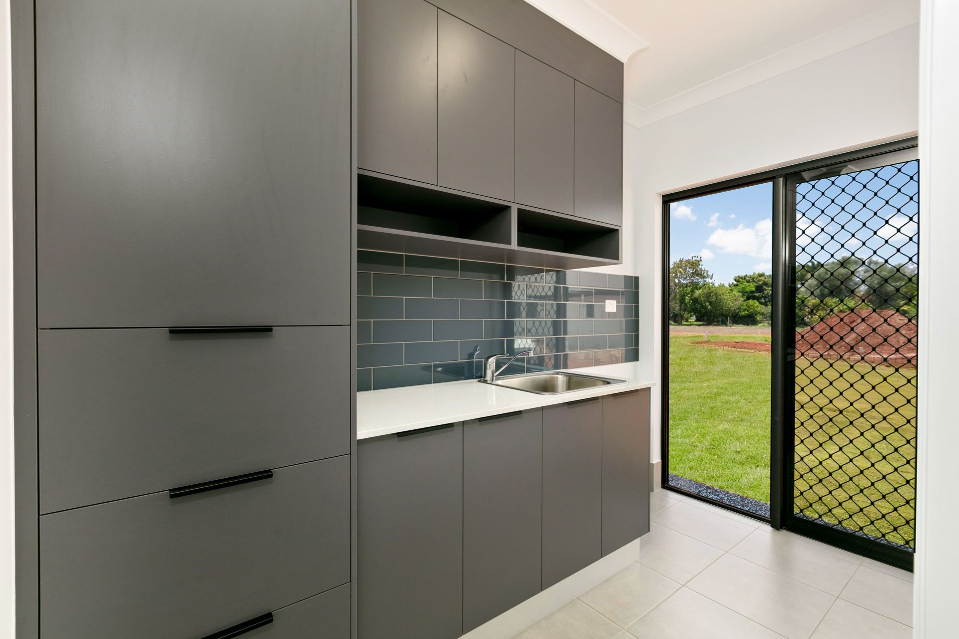 A Modern Laundry Room With Grey Cabinetry — Ashlee Jones Homes in Gordonvale, QLD