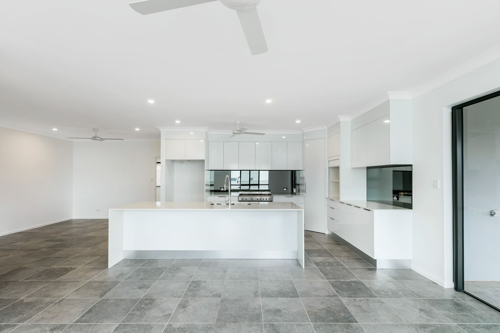 A Bright, Minimalist Modern Kitchen Featuring White Cabinets — Ashlee Jones Homes in Gordonvale, QLD
