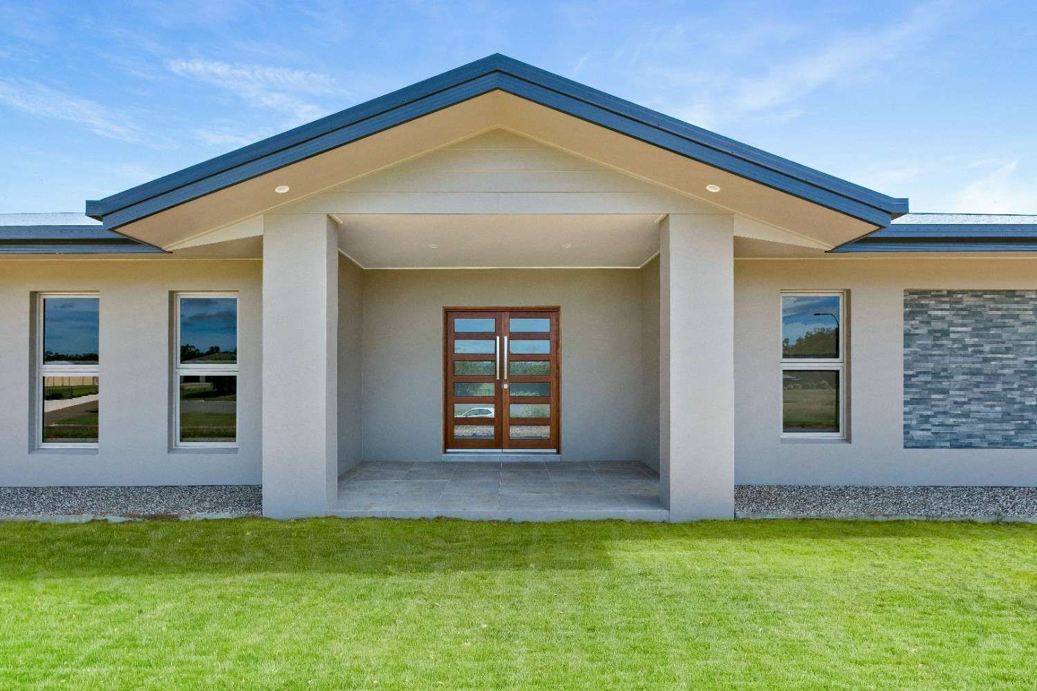 A White House With a Blue Roof and a Wooden Door — Ashlee Jones Homes in Gordonvale, QLD