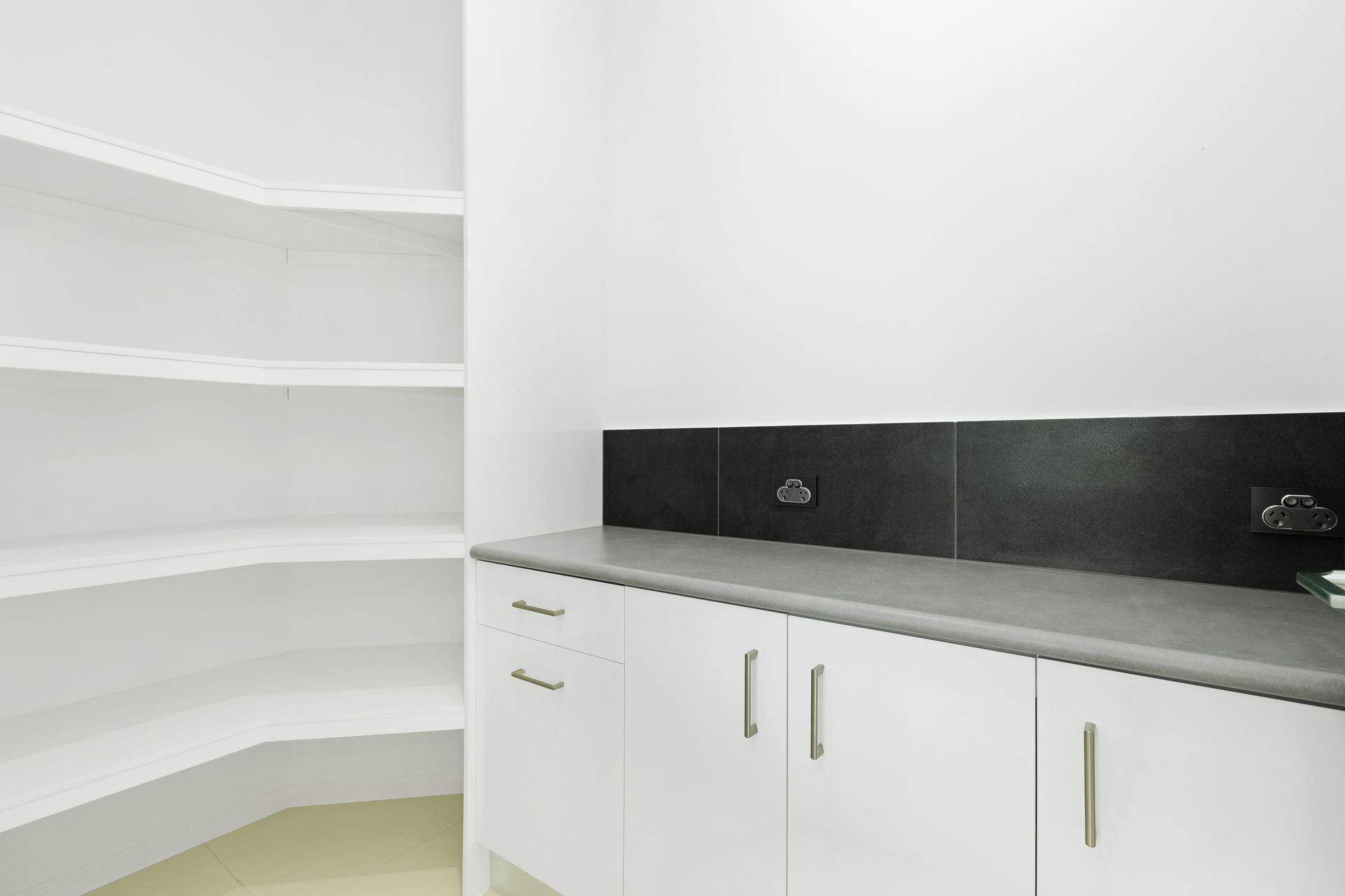 A Modern, Bright Walk-in Pantry Featuring White Cabinets — Ashlee Jones Homes in Gordonvale, QLD