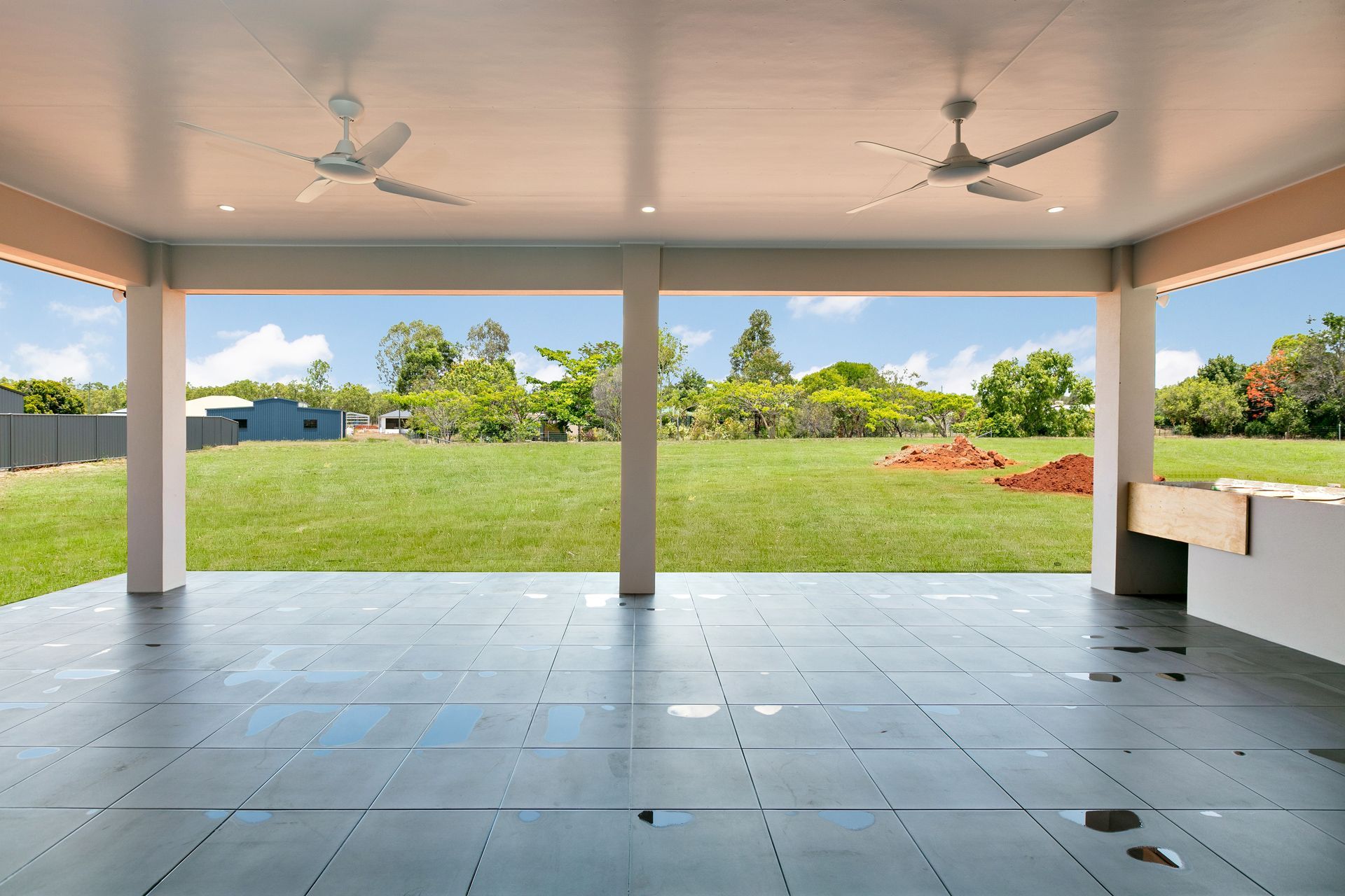 A Covered Patio With a Gray Tiled Floor, Two Ceiling Fans — Ashlee Jones Homes in Gordonvale, QLD