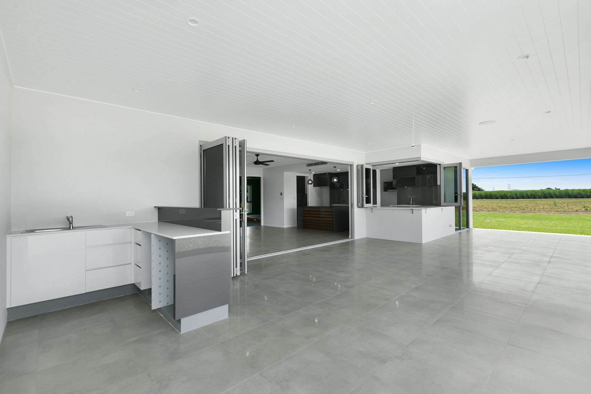 A Modern, Open-plan Indoor-outdoor Living Area Featuring White Walls — Ashlee Jones Homes in Gordonvale, QLD