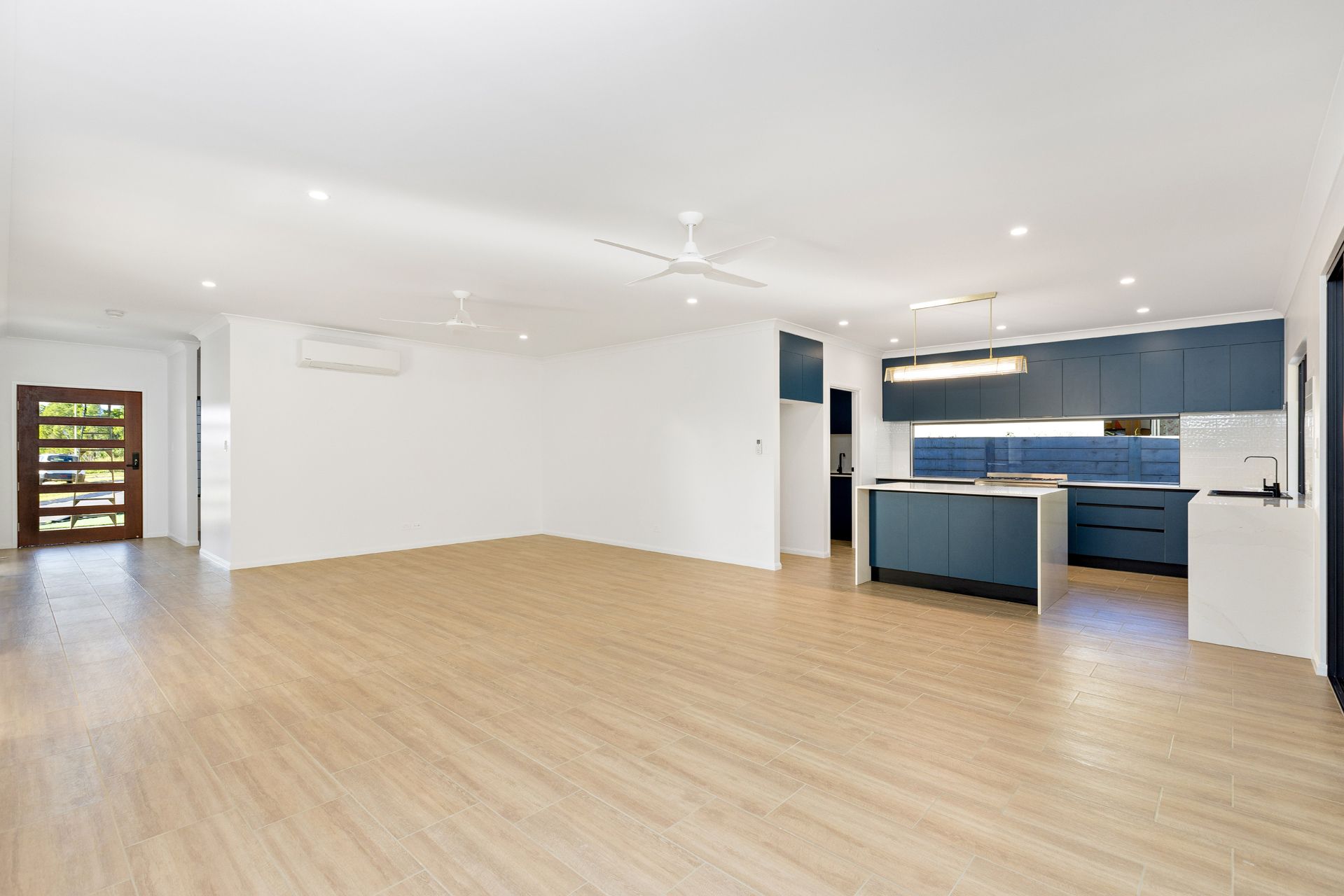 An Open-plan Living Room With Light Wood-look Flooring — Ashlee Jones Homes in Gordonvale, QLD