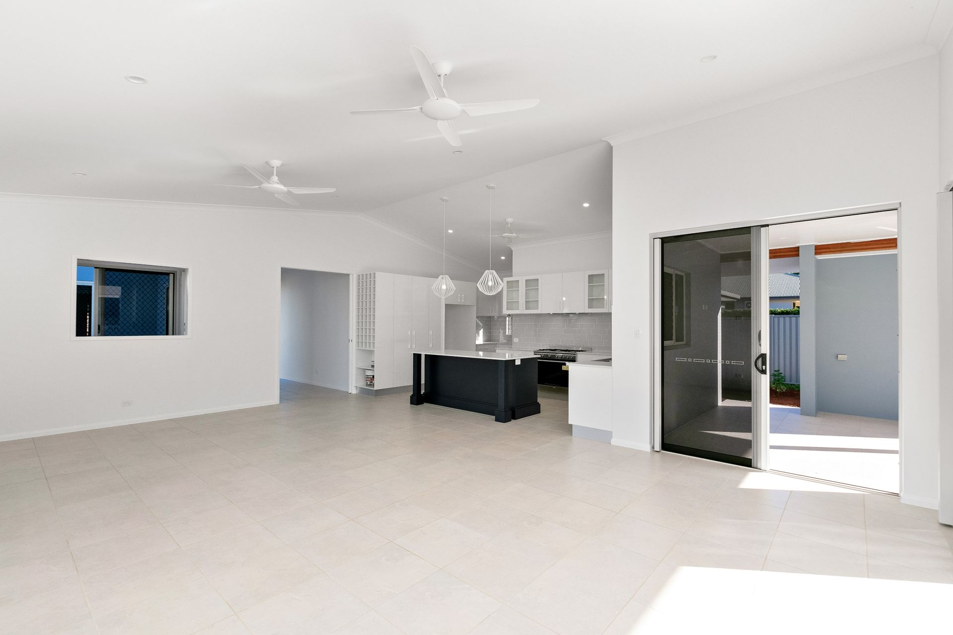A Bright, Open-plan Living and Kitchen Area With White Walls — Ashlee Jones Homes in Gordonvale, QLD