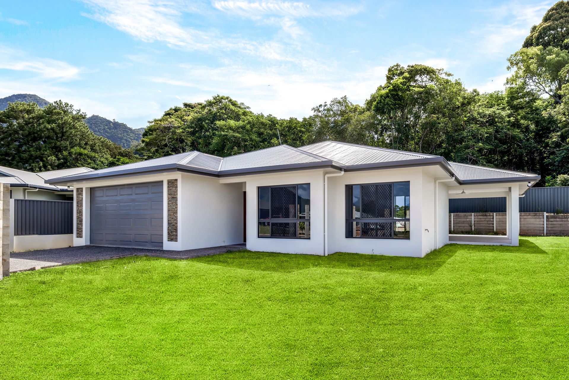 A Single-story White House With a Grey Roof and Garage — Ashlee Jones Homes in Gordonvale, QLD