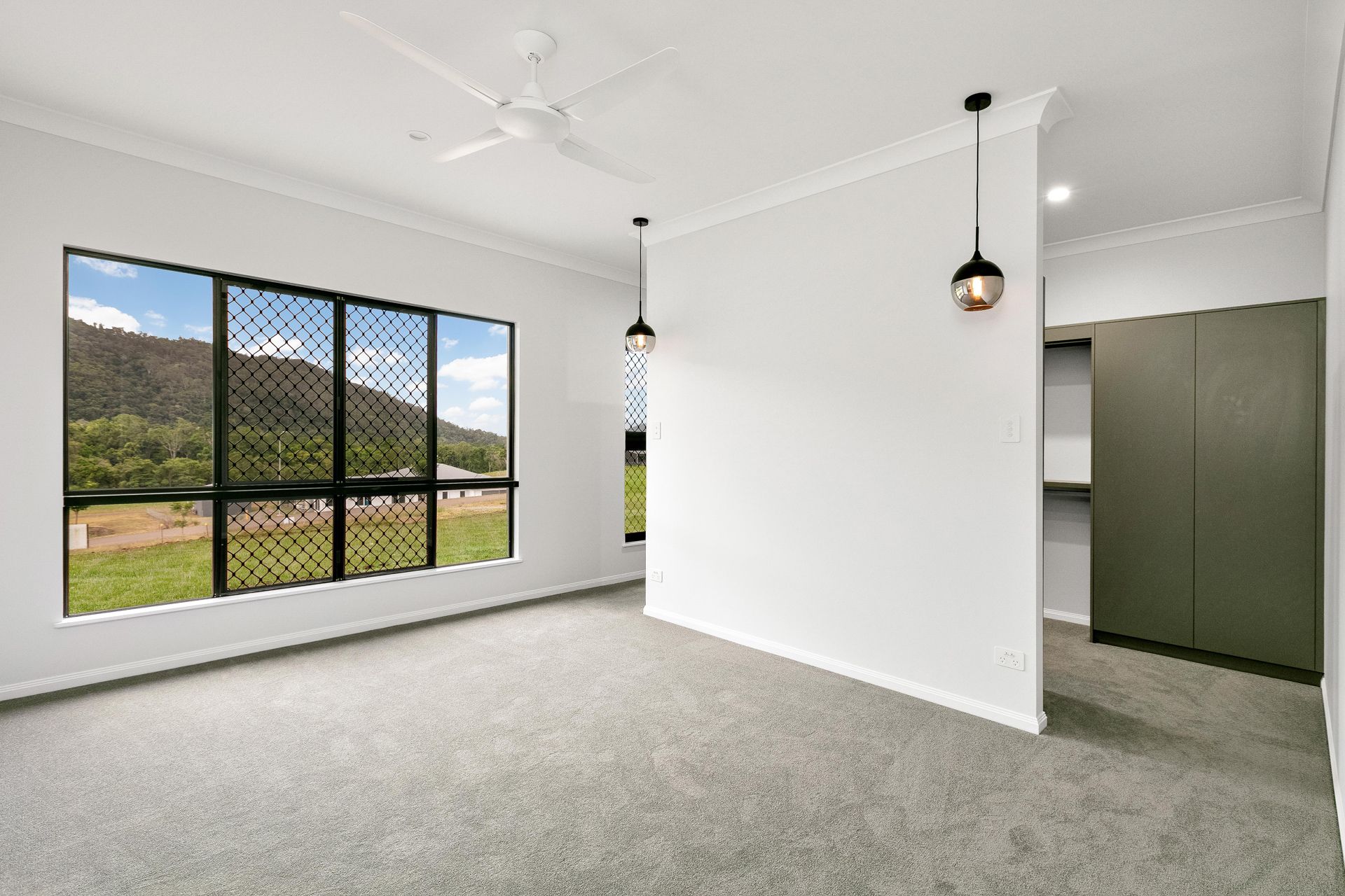 A Bright, Empty Bedroom With Grey Carpet — Ashlee Jones Homes in Gordonvale, QLD