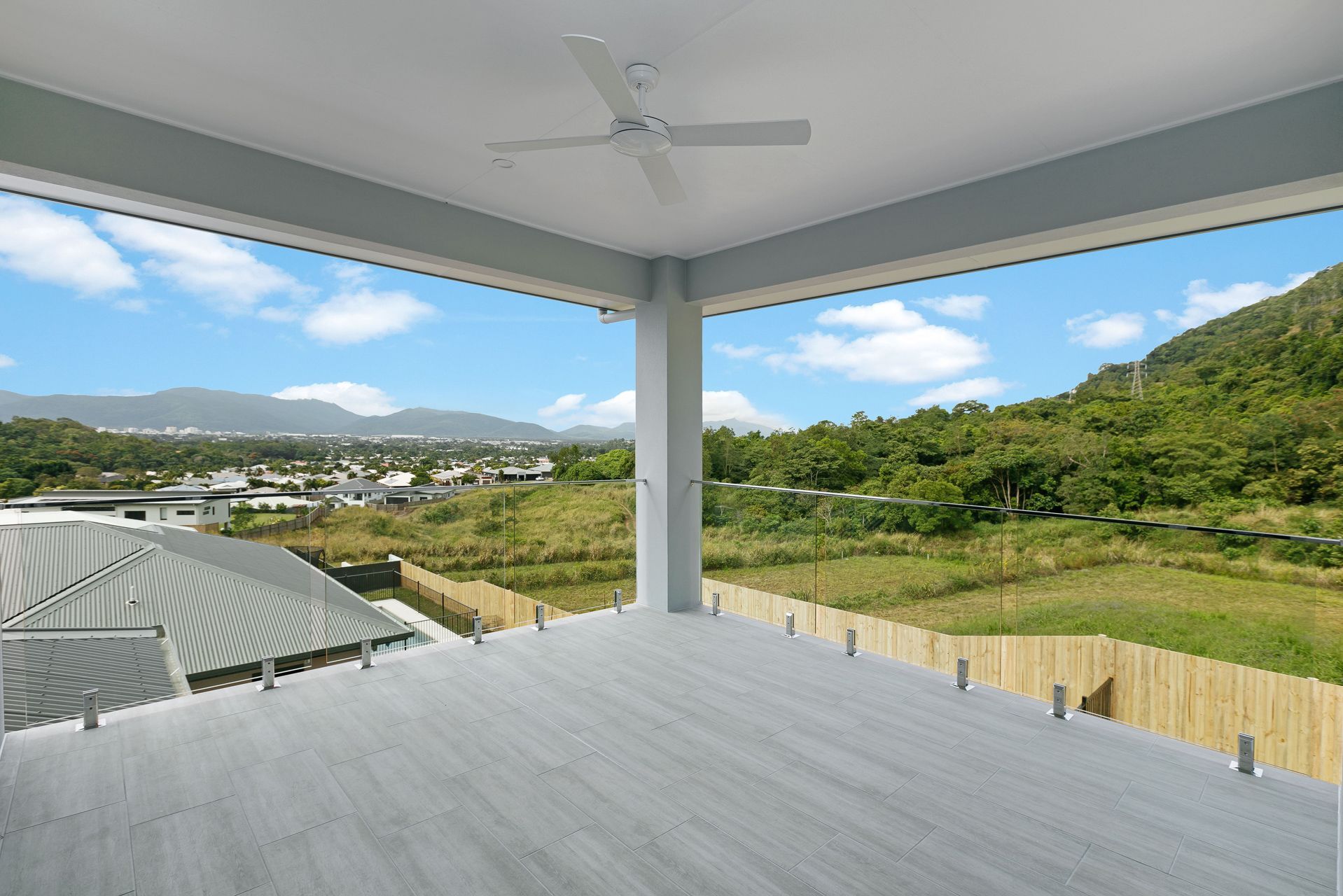 A Spacious, Covered Outdoor Balcony With Light Gray Decking — Ashlee Jones Homes in Gordonvale, QLD