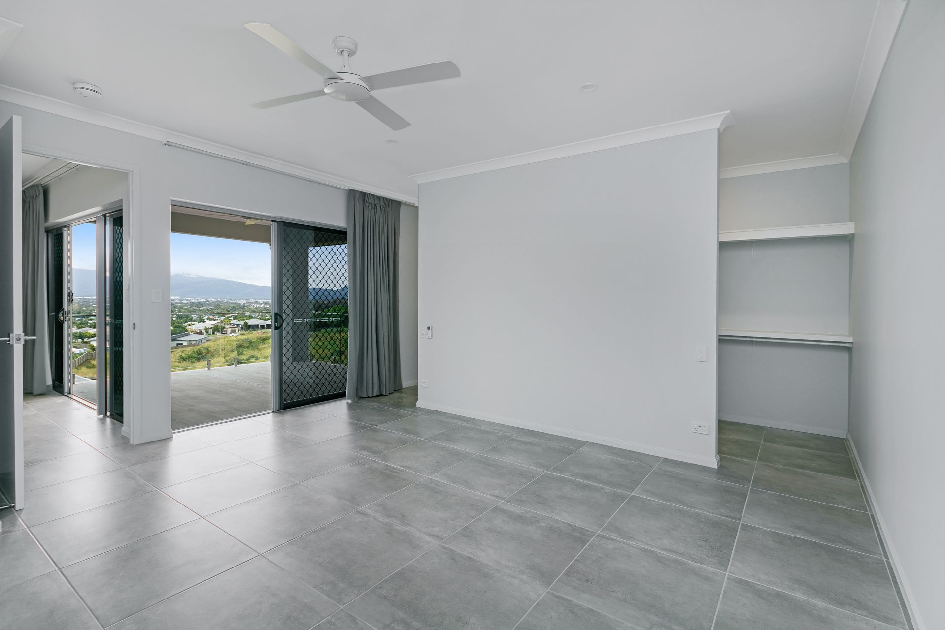 An Empty Room With Gray Tiled Floors, Light Gray Walls — Ashlee Jones Homes in Gordonvale, QLD