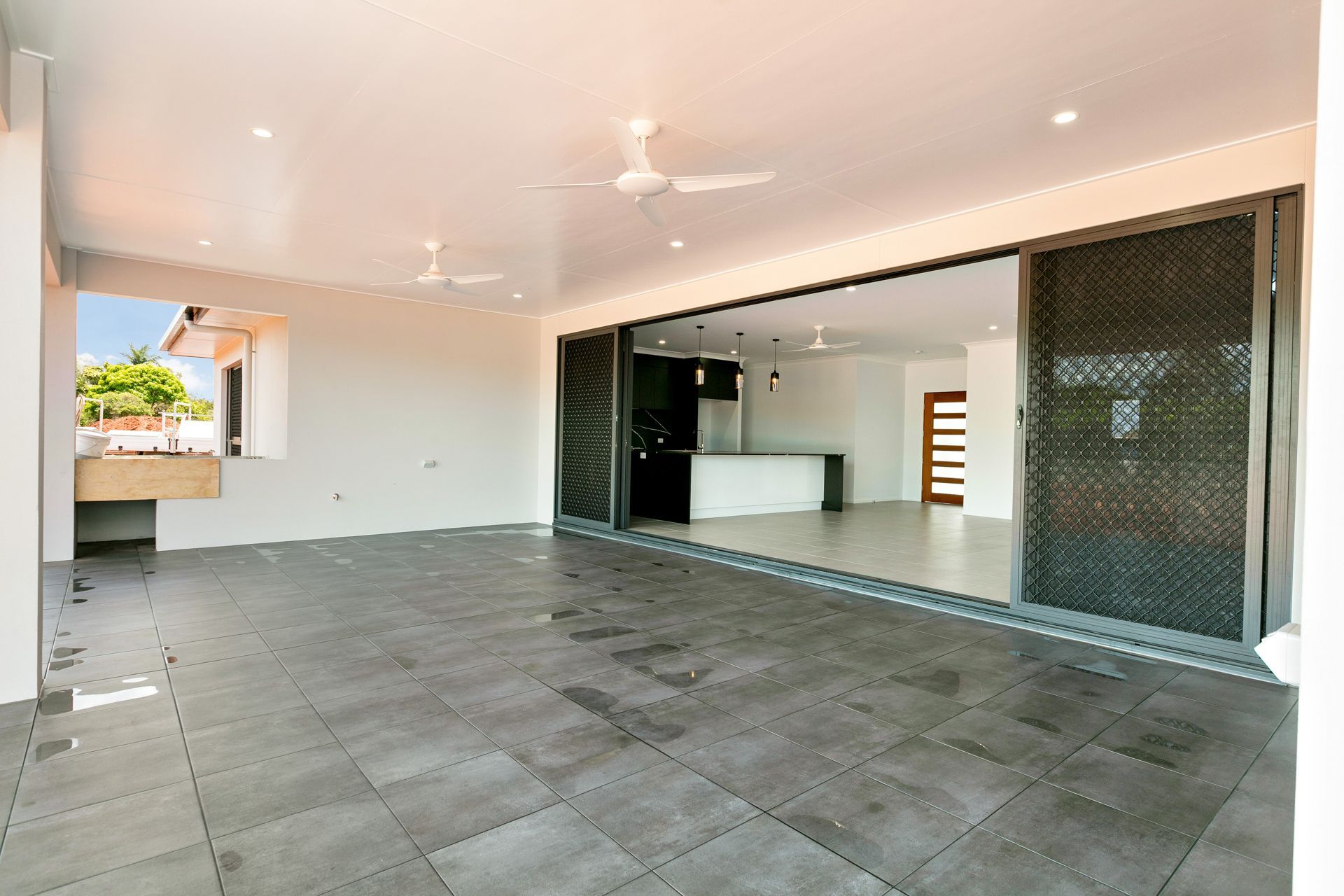 A Wide, Covered Patio With Gray Tile Flooring — Ashlee Jones Homes in Gordonvale, QLD