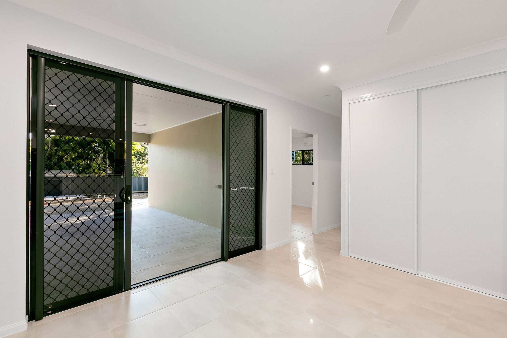 A Bright, Minimalist Room With Large Black Screen Sliding Doors — Ashlee Jones Homes in Gordonvale, QLD