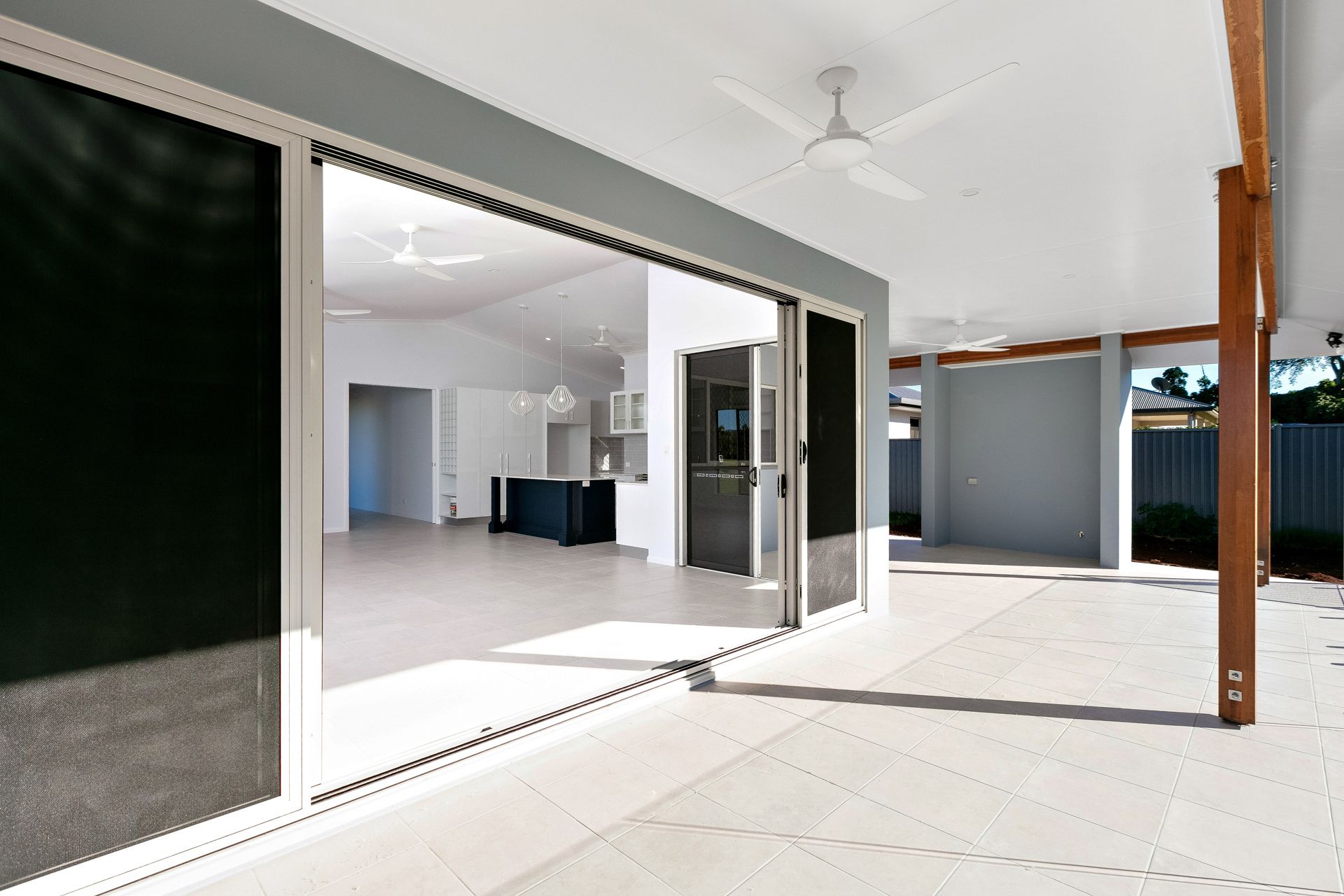 A Covered Outdoor Patio With a Large Sliding Door Opening Into a Modern — Ashlee Jones Homes in Gordonvale, QLD