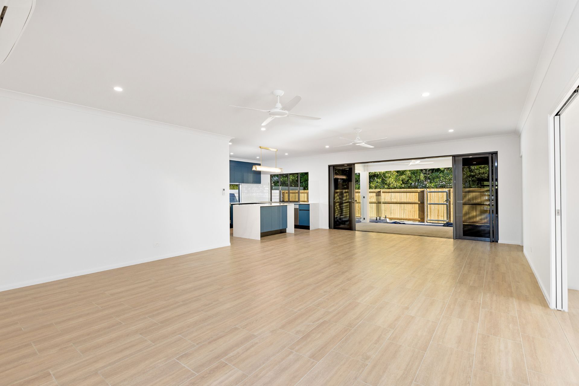An Open-plan Living Room With Light Wood-look Flooring — Ashlee Jones Homes in Gordonvale, QLD
