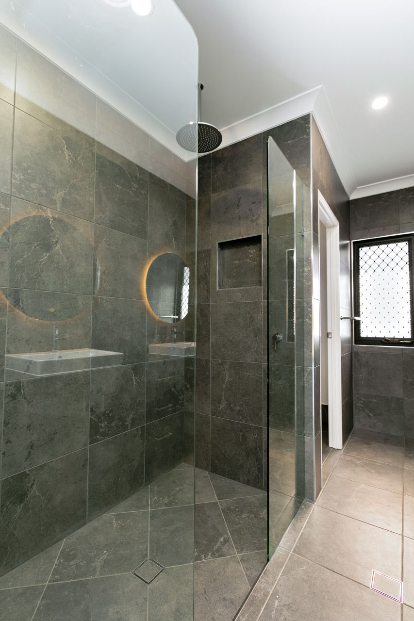 A Walk-in Shower With Dark Grey Stone Tiles, a Glass Partition — Ashlee Jones Homes in Gordonvale, QLD