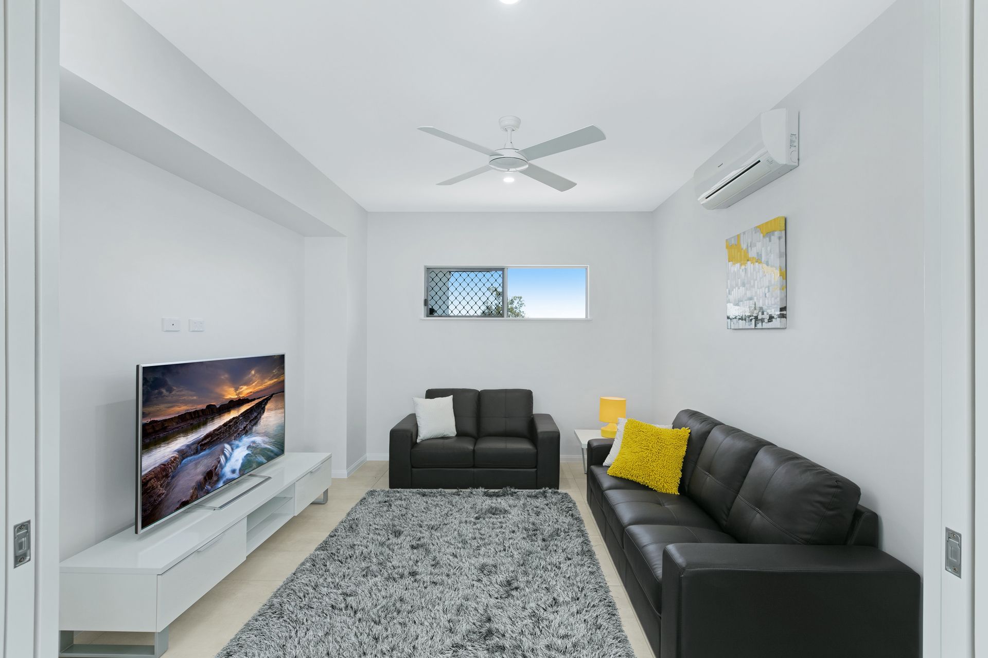 A Modern Living Room With a Tv, a White Media Console — Ashlee Jones Homes in Gordonvale, QLD