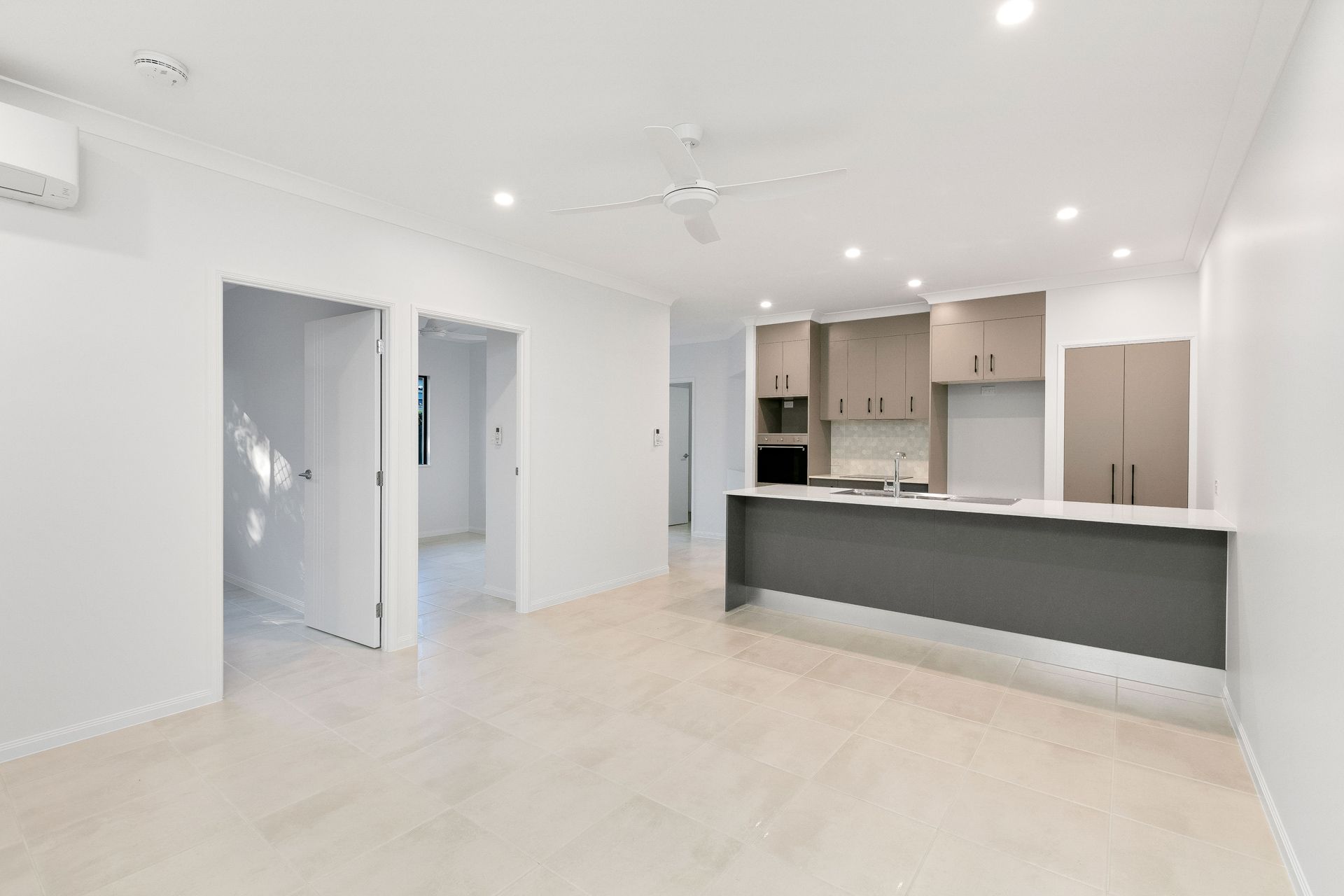 A Modern, Empty Living Room With Light Tiled Floors — Ashlee Jones Homes in Gordonvale, QLD