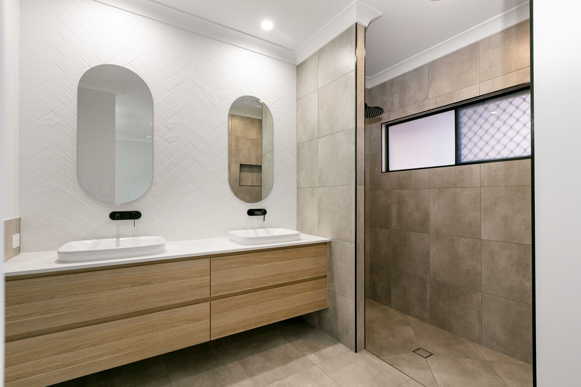 A Modern Bathroom With a Wood Vanity, Dual Oval Mirrors — Ashlee Jones Homes in Gordonvale, QLD
