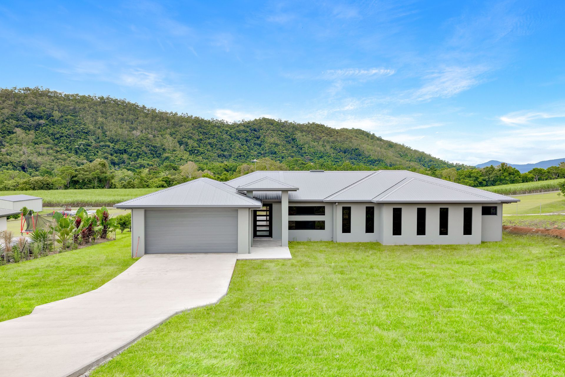 A Modern Gray Single-story House With a Garage and Driveway — Ashlee Jones Homes in Gordonvale, QLD