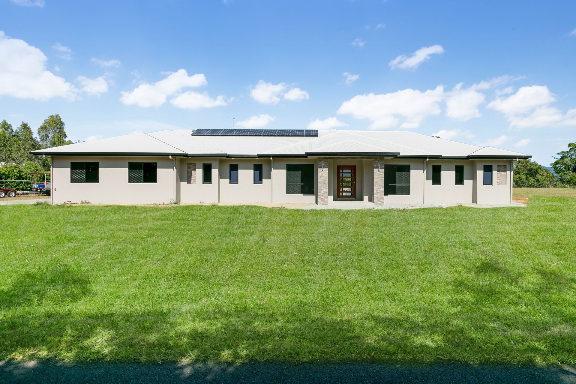 A Modern, Beige, Single-story House With a Grey Roof Sits on a Large — Ashlee Jones Homes in Gordonvale, QLD
